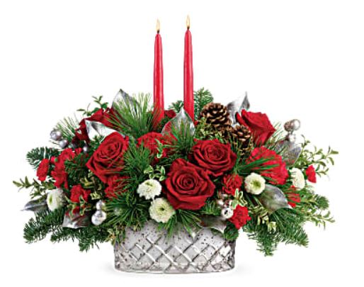 A Magical Christmas Centerpiece - Brimming with festive Christmas red roses and lit by two glowing tapers, this gorgeous magical centerpiece!  Red roses, red carnations, red miniature carnations, and white button spray chrysanthemums are accented with noble fir, white pine, oregonia, lemon leaf, and red candles.  Orientation: All-Around