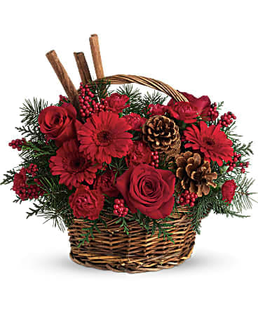Cinnamon Berry Basket - The scents of the season! Christmas greens, bold red flowers and cinnamon sticks make this a fragrant floral arrangement for Christmas gatherings. A handled basket of red flowers including roses, red gerbera daisies and carnations is topped with festive cinnamon sticks. 