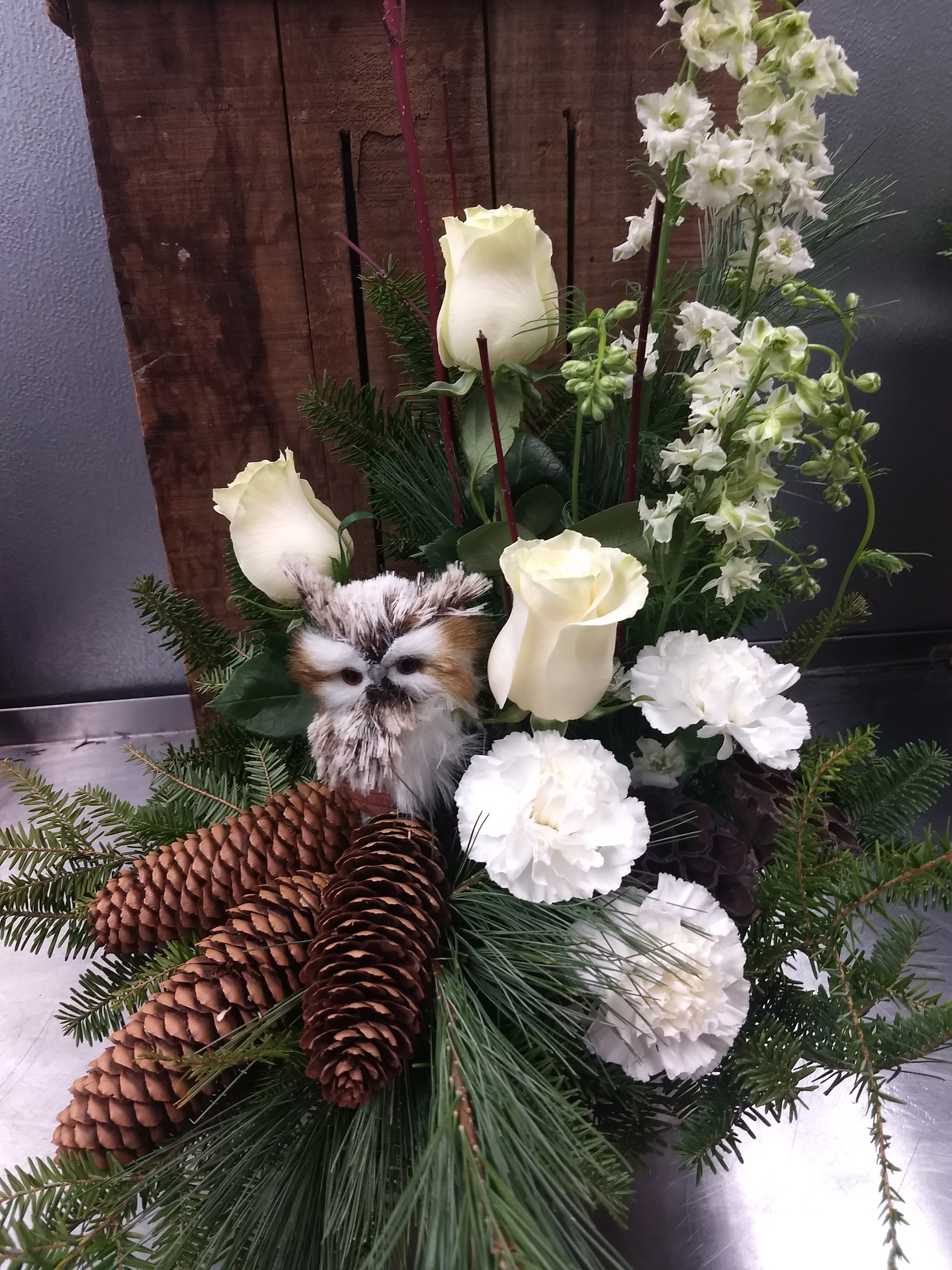 Winter Owl - This fun playful winter design is in a wooden box, with natural pine cones, white roses, carnations and a playful owl.