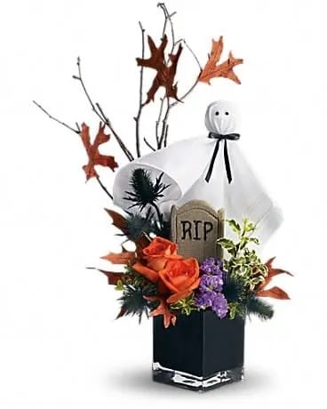Ghostly Gardens - What fun! A fabulous ghost boo-quet. Perfect for friends, family and colleagues because everybody loves a friendly ghost, especially when he's surrounded by fresh flowers. Orange roses, blue eryngium, purple statice, a birch branch, oak leaves and more are presented in a black cube vase with a googly-eyed ghost. Just scream and we'll send it today! 