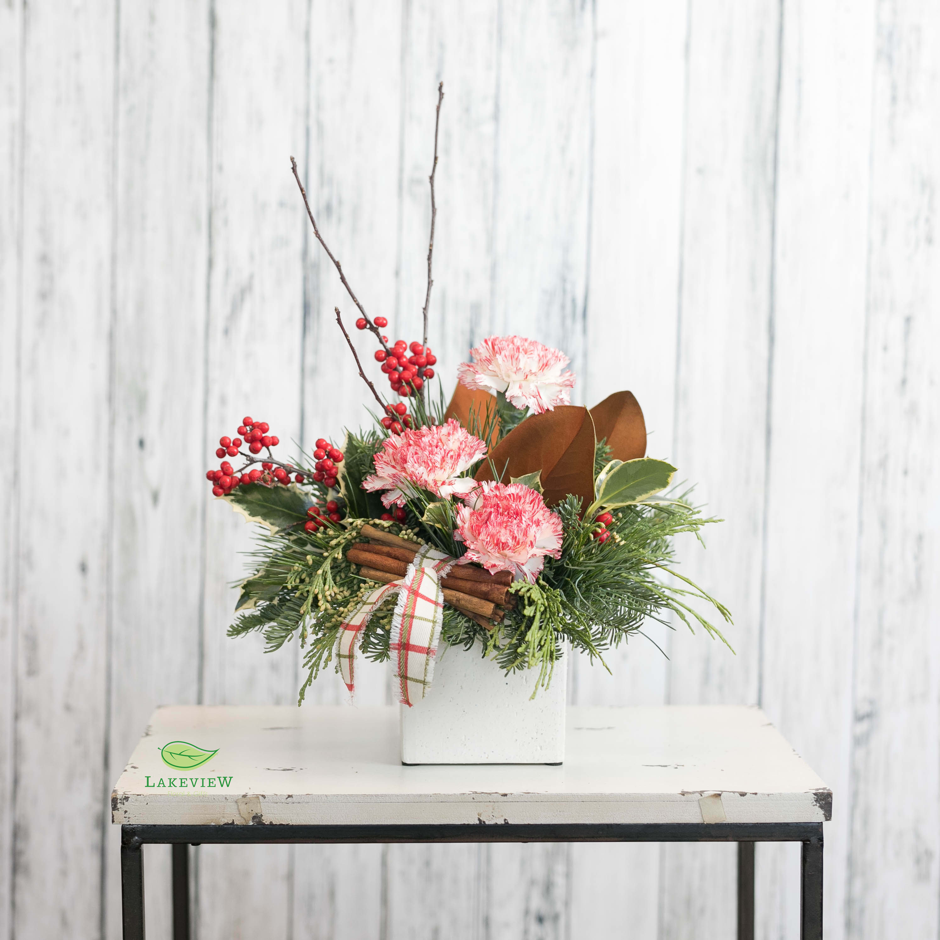 Carolers - Encourage anyone to break out into festive song with an arrangement like this!  Peppermint carnations with cinnamon sticks and velvety magnolia are the epitome of holiday cheer!  Approximately 14&quot; Tall X 10&quot; Wide 