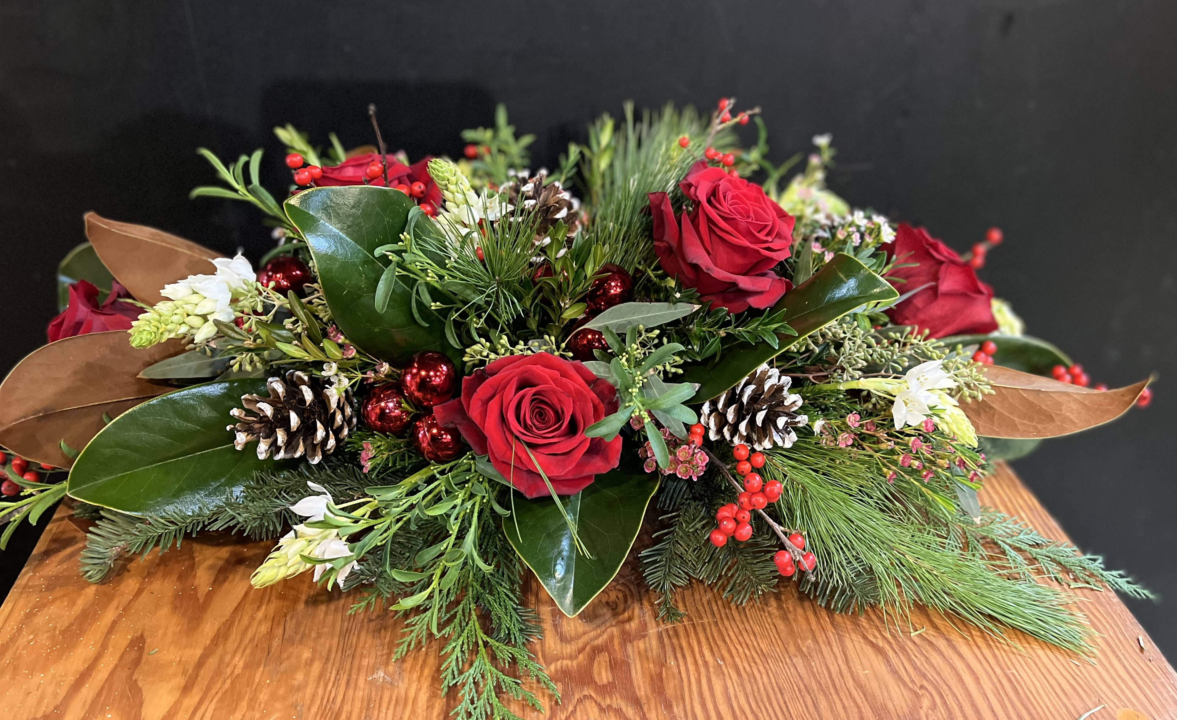 Christmas Celebrations  - Celebrate The Holiday with this elegant centerpiece.  . Red roses , red berries , pine cones , star of Bethlehem, and mixed premium evergreens artfully arranged .   Approximately 30”L 