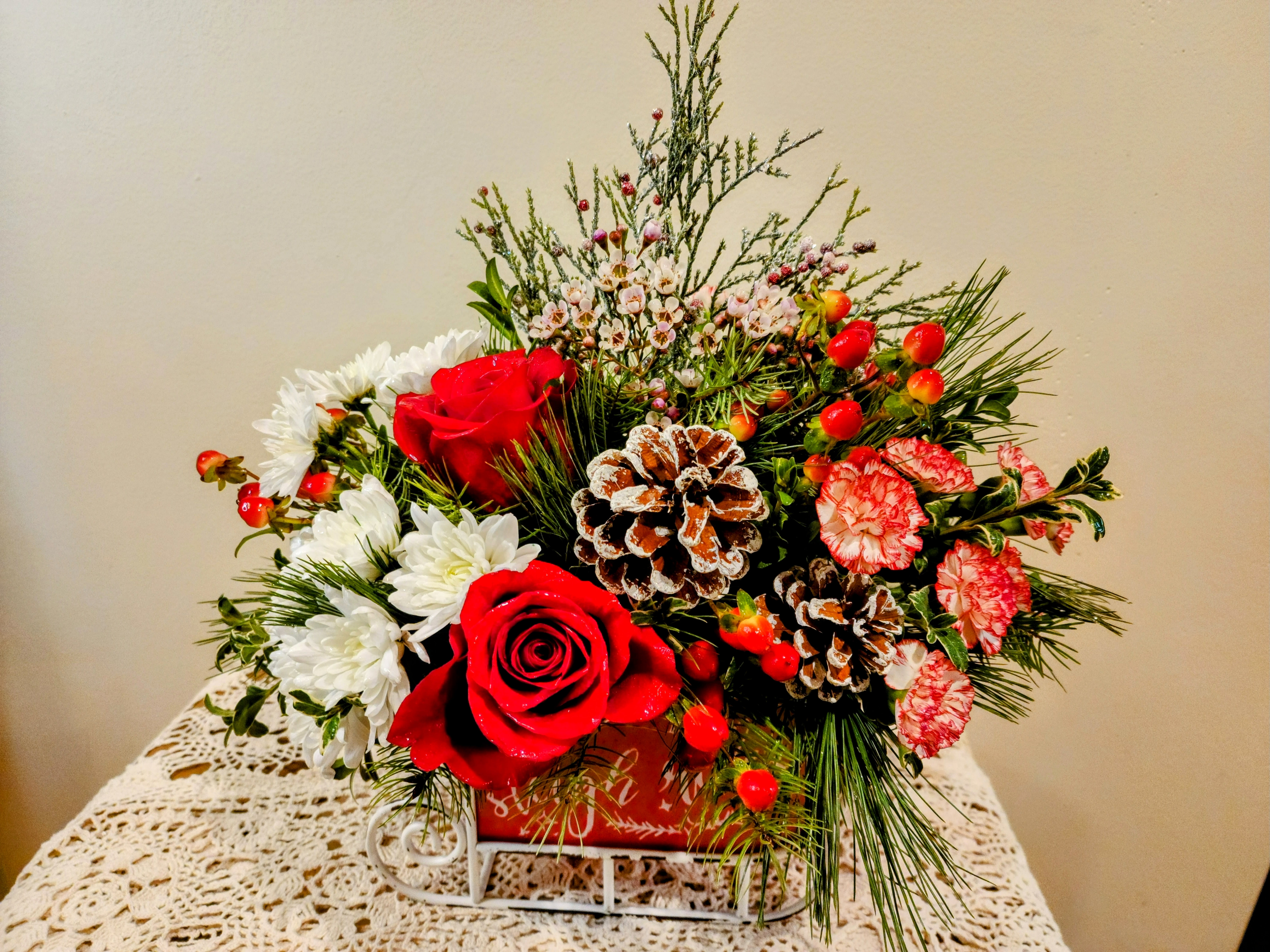 Santa's Sleigh - Roses, mini carnations, mums and Christmas Greens fill this sleigh in time for the holidays.