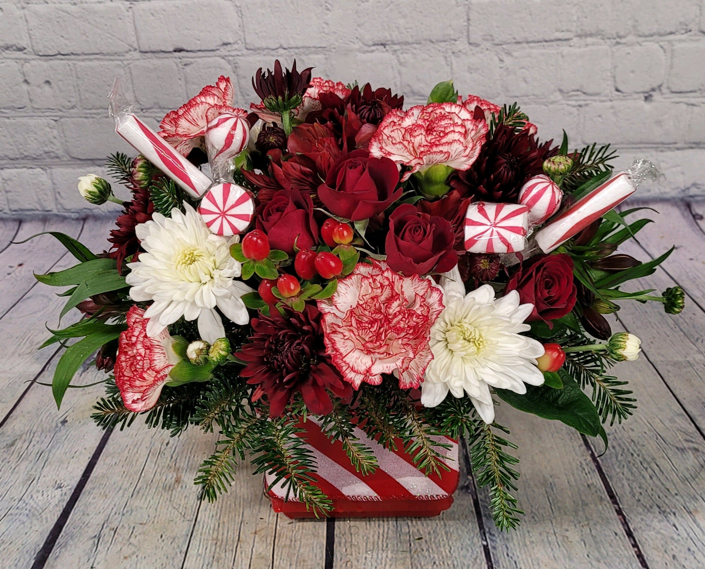 Peppermint Winter - Minty fresh and oh so cute! Our &quot;Peppermint Winter&quot; Bouquet is filled with a variety of fresh pine, candy-cane carnations, holiday chrysanthemums, red spray roses, hypericum berries, &amp; adorable peppermint picks. 