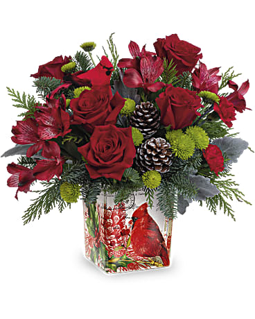 Teleflora's Ode To The Cardinal Bouquet - This Christmas cardinal delivers your best wishes for a joyful holiday season with stunning crimson blooms and fresh-from-the-forest greens. The vintage-inspired cube vase doubles as a candleholder!