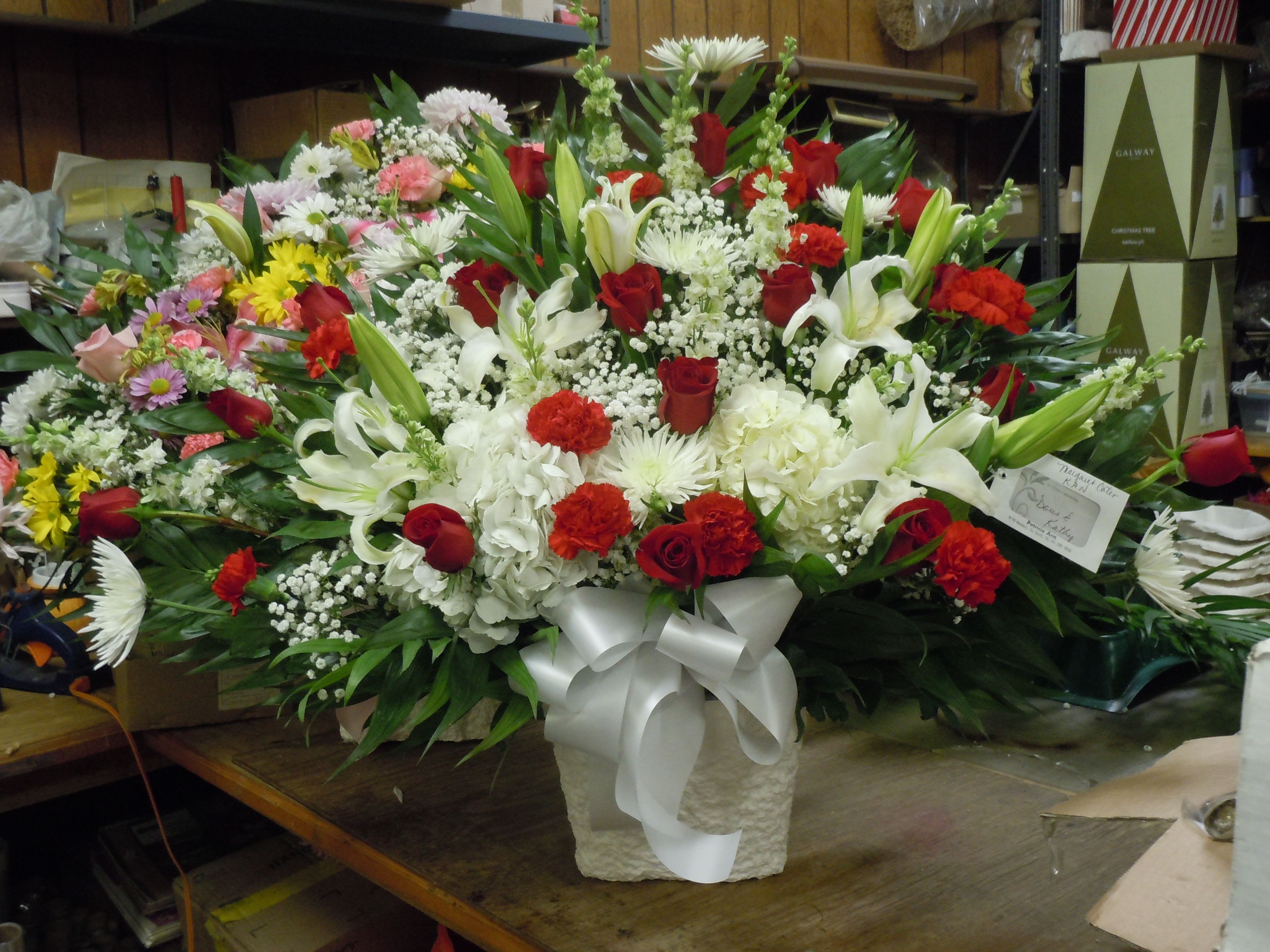TB3 Traditional Basket - TB2 Sympathy mache - includes white spider mums,  white daisies, red roses,  red carnations, red roses, white hydrangea, white snap dragons, baby's breath, greens, and bow.  Banners not included $15 + per banner   Substitutions may apply pending flower availibilty