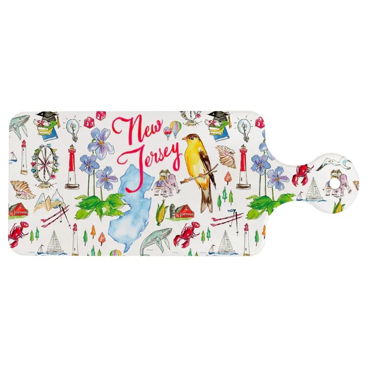 NJ State Cuterie - Celebrate the Garden State with this glossy ceramic trivet, artfully splashed with watercolor illustrations of iconic New Jersey sights. Shaped like a petite paddle board with a convenient hanging hole, it protects tabletops from hot dishes and doubles as a charming little serving or display piece. Approximate dimensions are 11.5 x 4.75 x .25 inches.