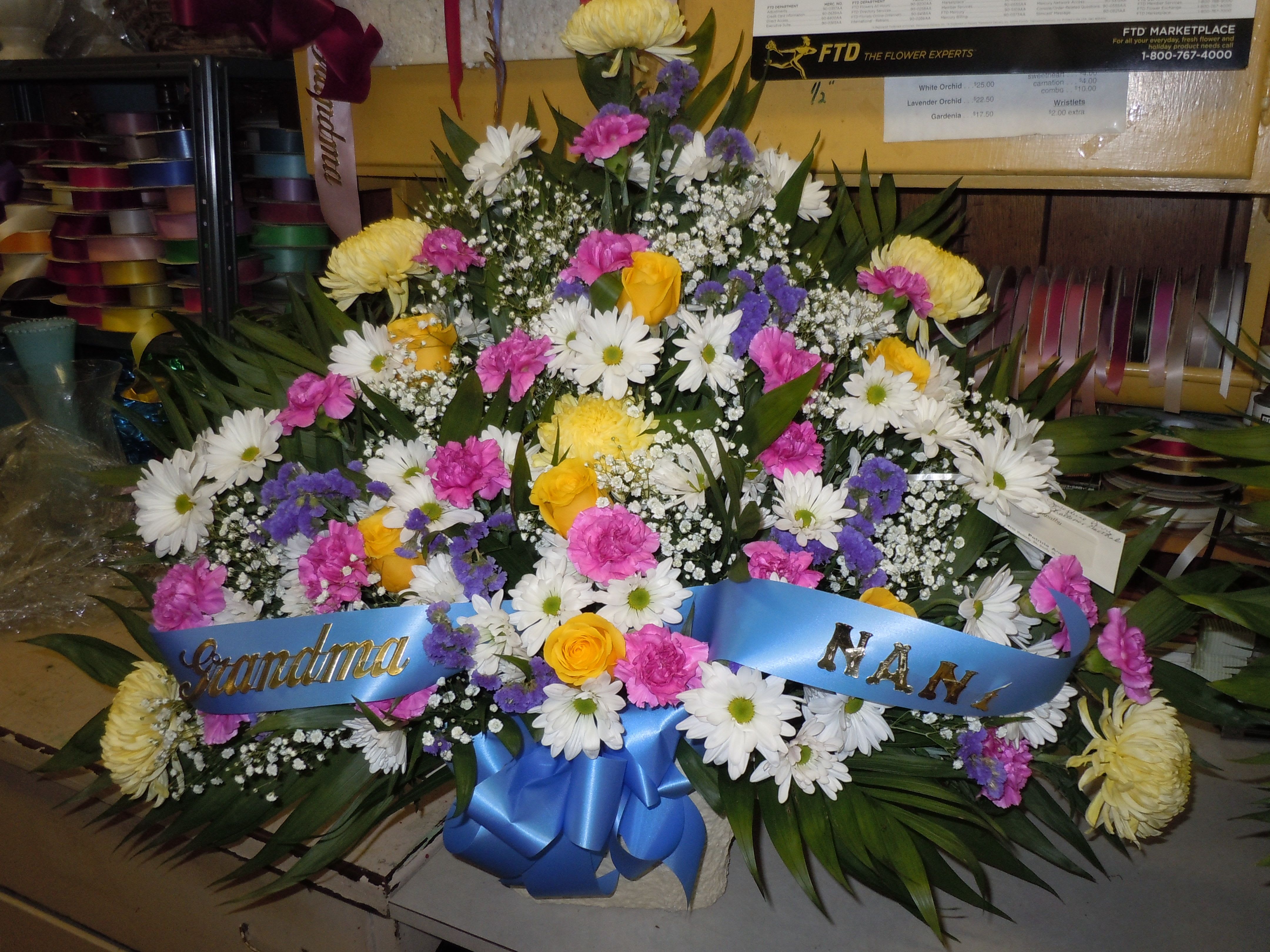TB12 Traditional Basket - Sympathy mache - includes yellow sprider mums, white daisies, ferida  carnations, purple statice, yellow roses, baby's breath, greens, and bow.  Banners not included $15 + per banner   Substitutions may apply pending flower availibilty