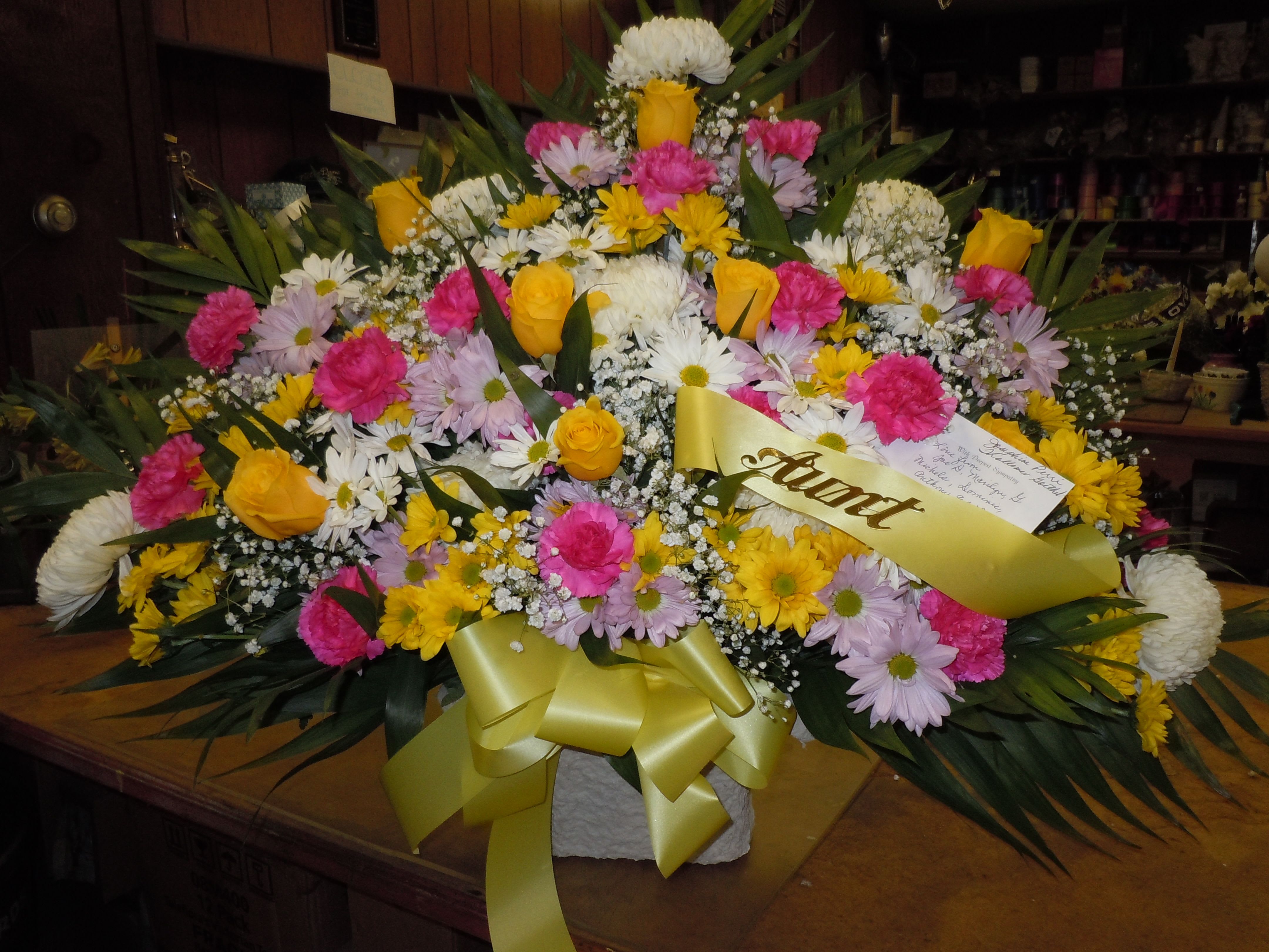 TB13 Traditional Basket - Sympathy mache - includes white spider mums, white and alvender daisies, hot pink carnations, yellow roses, baby's breath, greens, and bow.  Banners not included $15 + per banner   Substitutions may apply pending flower availibilty