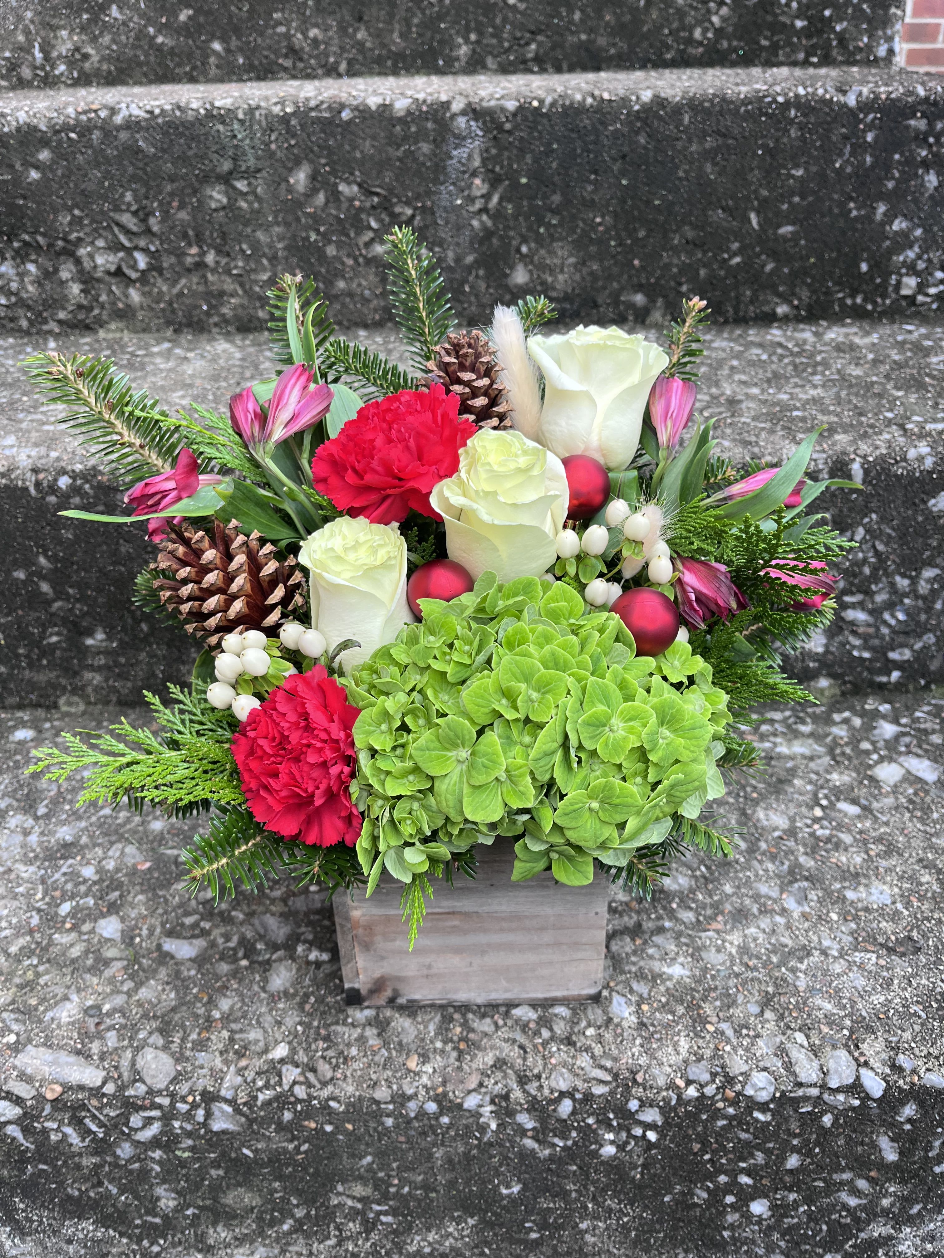 Tis The Season  - A beautifully crafted holiday arrangement filled with hydrangea, alstroemeria, hypericum berries, roses, carnations, pinecones, ornaments, and fresh Christmas greens—perfect for adding festive elegance to any home or event. 