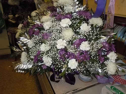 TB22 Traditional Basket - A mixture of purple daisies, white carnations, pink roses, white fuji mums, baby's breath, greens touched silver and purple box bow  Banner - $15.00 + extra  Substitutions may apply due to flower availability