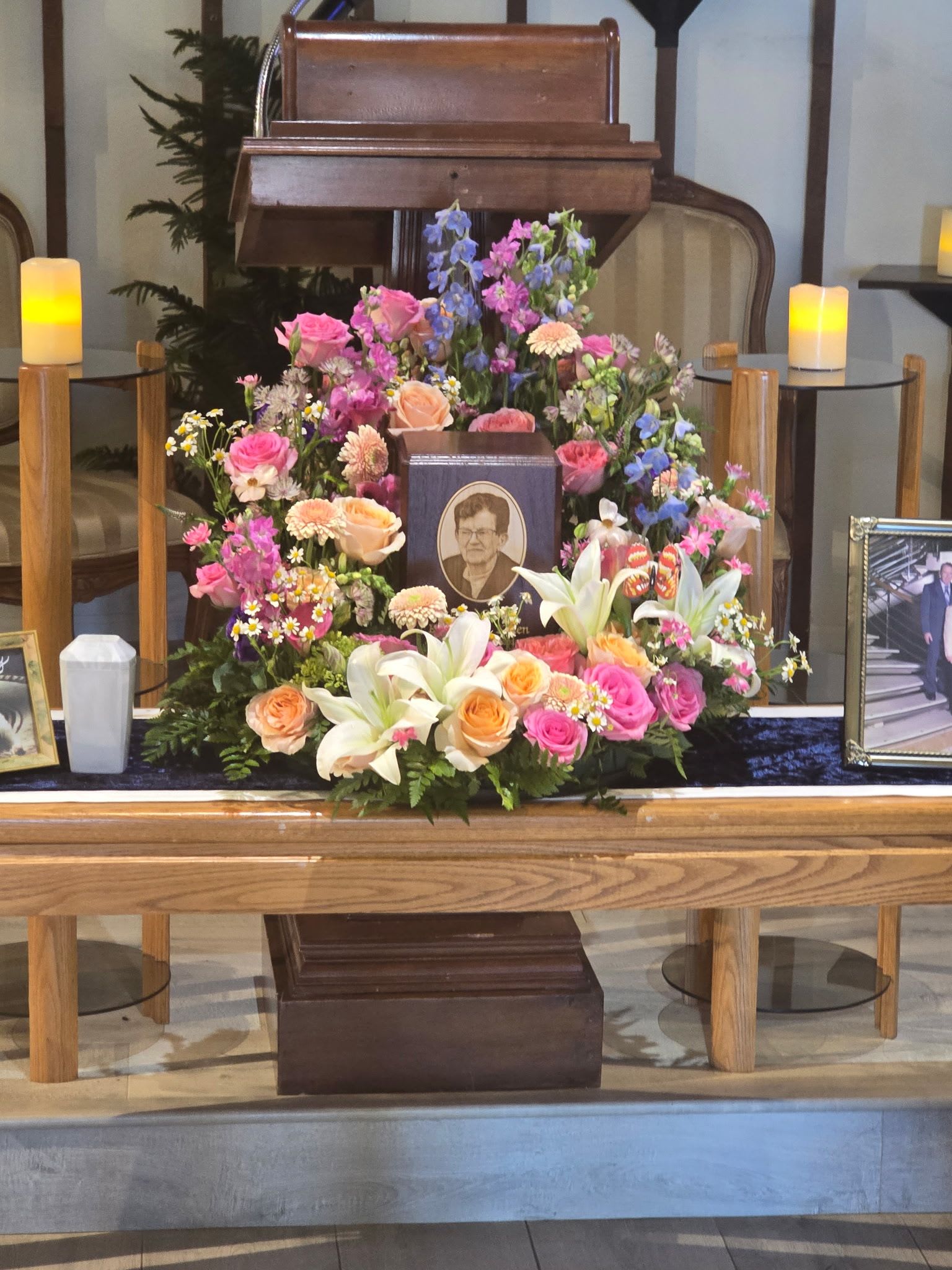 GARDEN SPLENDOR URN WREATH - THIS AMAZING TRIBUTE IS LIKE LOOKING AT A GARDEN PATH, FILLED WITH ROSES, LILIES, DAISIES, AND OTHER MEADOW WILDFLOWERS. A TRULY STUNNING STATEMENT TO EXPRESS YOUR LOVE. 