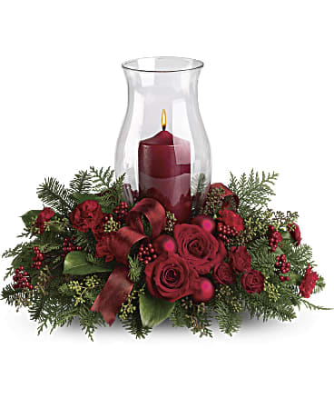 Holiday wishes Centerpieces  -  This beautiful Christmas centerpiece with its classic glass hurricane and red pillar candle, it also looks lovely on a mantle or entry table. Fragrant noble fir and seeded eucalyptus are the green backdrop to red roses, red carnations, red berries and matte red Christmas ornaments.