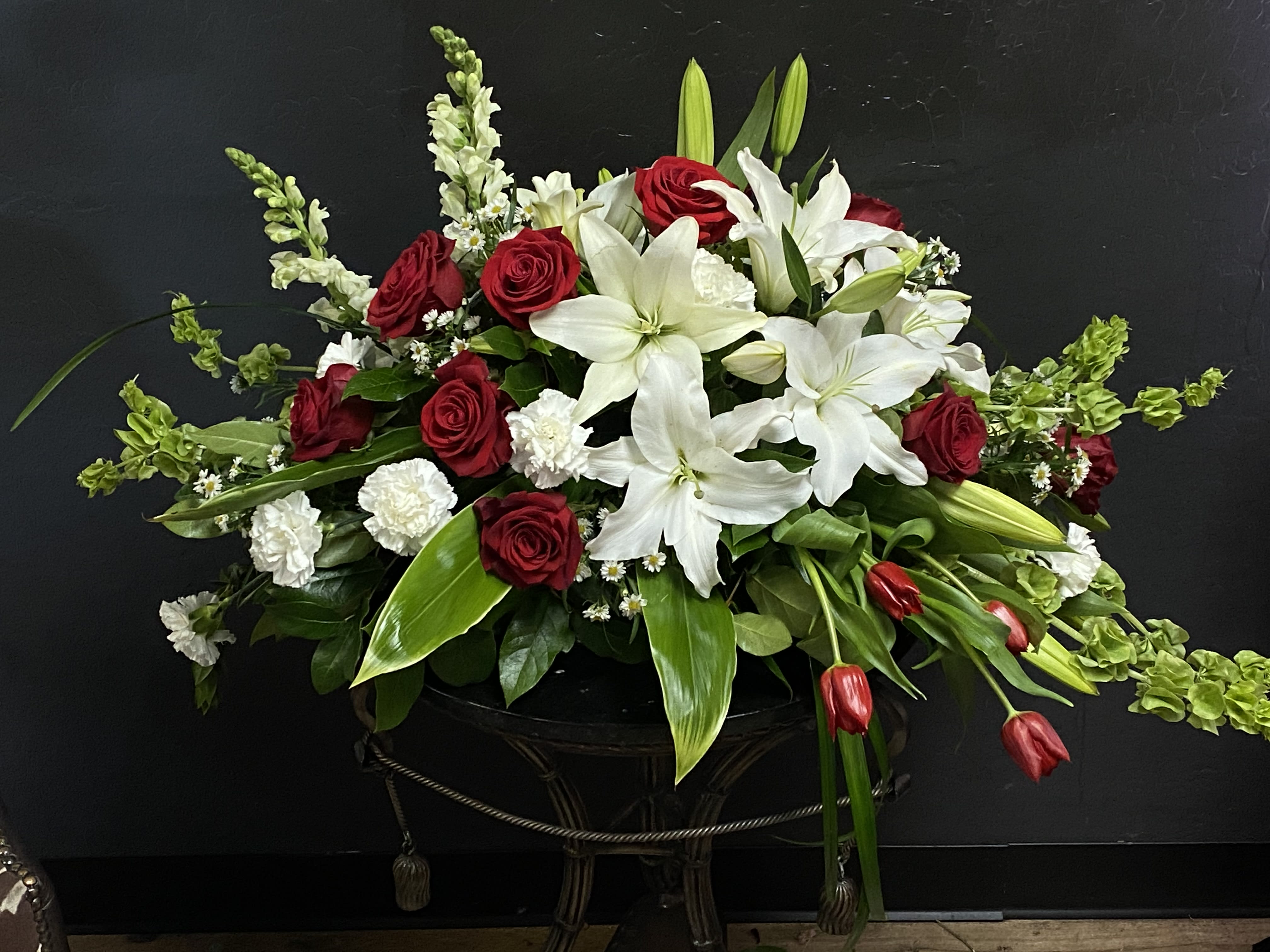 Resurrection Casket Spray - Resurrection Casket Spray inspires thoughts of comfort and peace to those wishing to pay their respects for the loss of the deceased. White tulips roses snapdragons Oriental lilies larkspur carnations and monte casino asters are accented by the bright green stems of Bells of Ireland and an assortment of the finest lush greens to create the perfect arrangement.