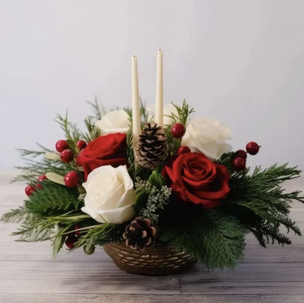 Blossom and pine centerpiece  - Graceful and festive, the Blossom &amp; Pine Centerpiece blends classic red and white roses with lush seasonal greenery, bright red berry accents, and natural pinecones for a warm holiday feel. Designed in an elegant gold base and finished with two slender white candles, this centerpiece brings a soft glow and timeless sophistication to any holiday table. Perfect for Christmas gatherings or seasonal décor, it’s a beautiful balance of tradition and refined elegance.
