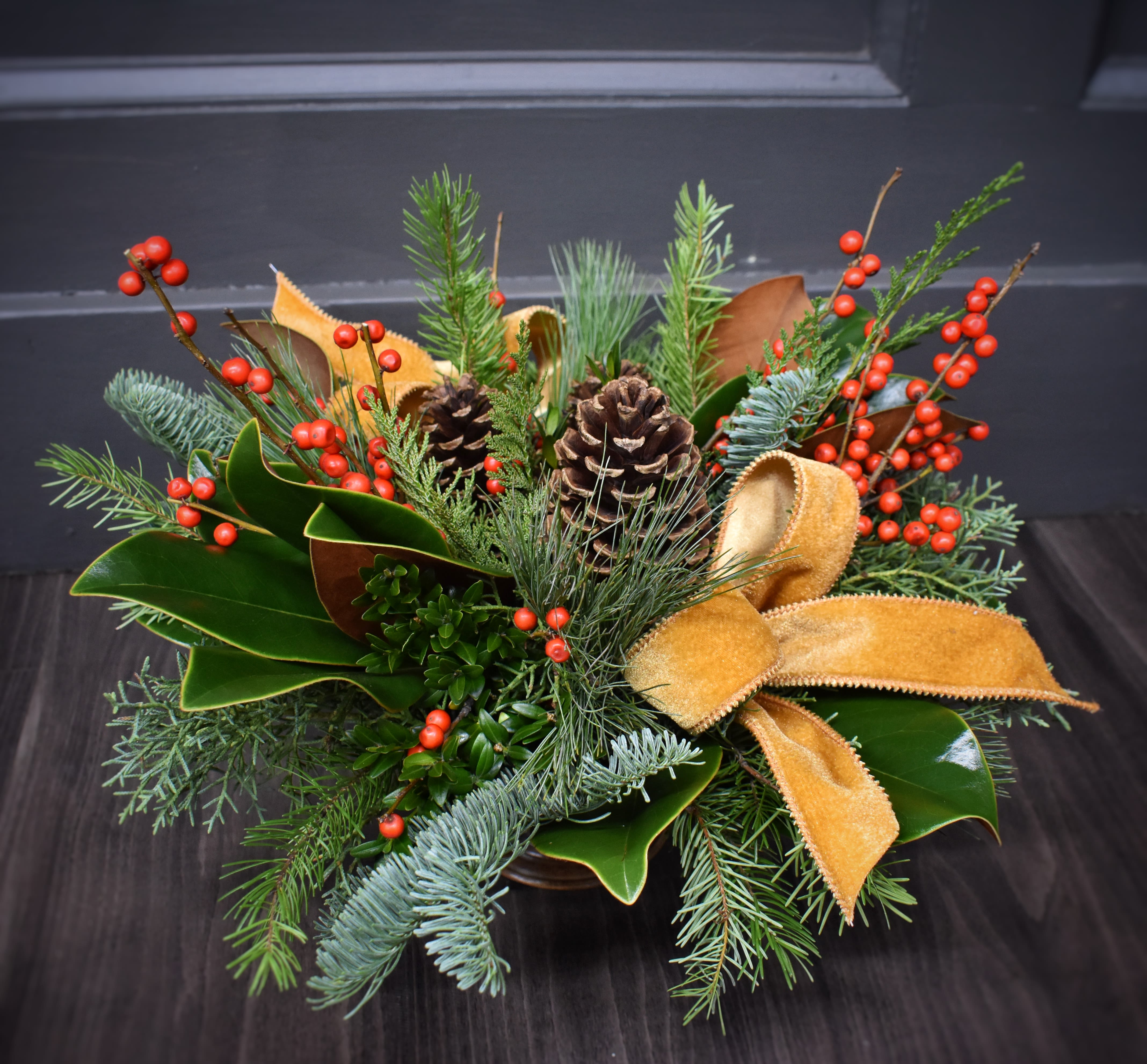 Classic Christmas Charm  - Nothing says classic Christmas like fresh evergreens, pinecones and berries! This charming arrangement will fill your home with the scents of the season and is accented with a classy velvet bow. Upgrade your arrangement and we'll add fresh blooms like premium red roses, and long lasting cymbidium orchid blooms. 