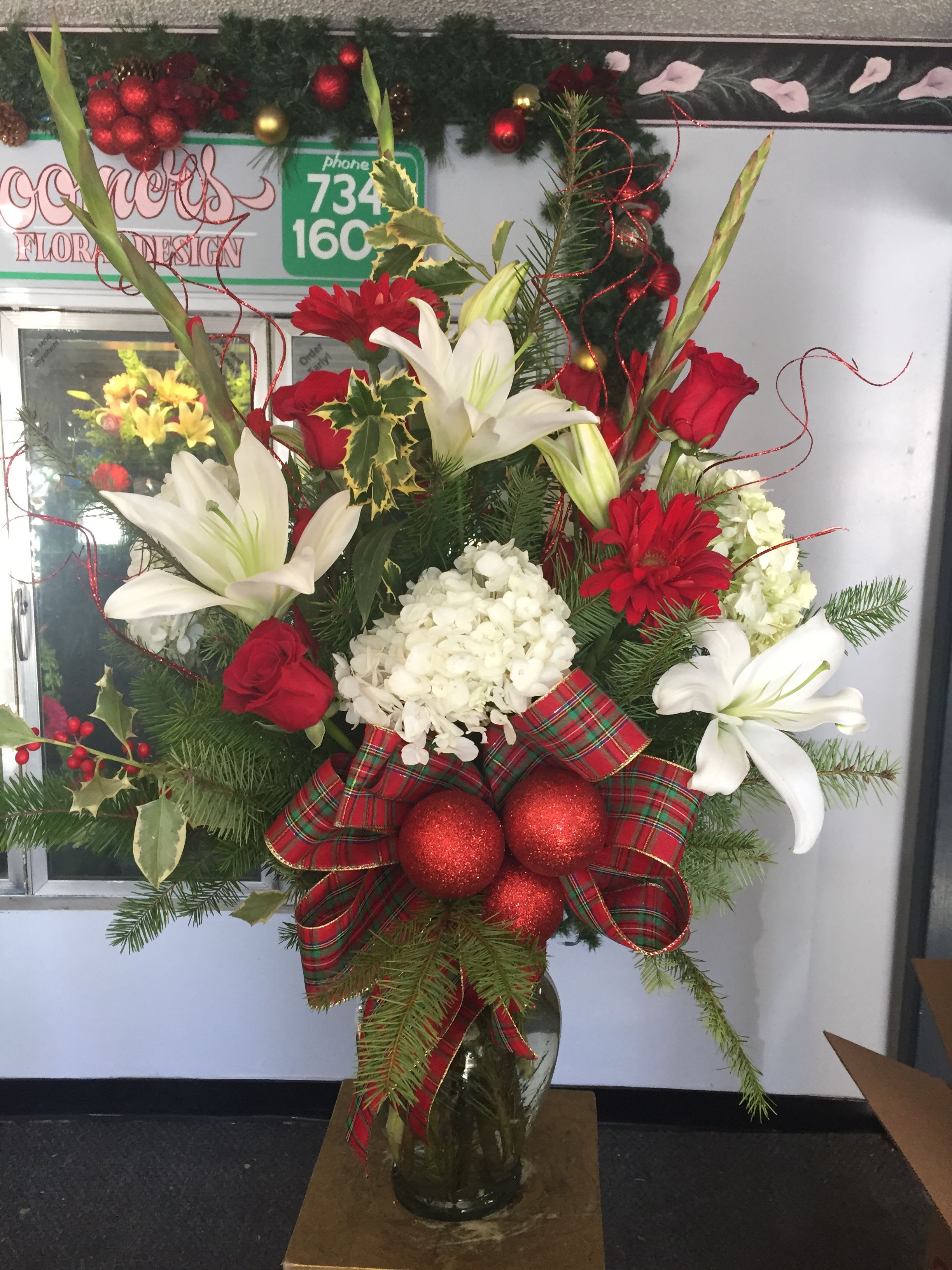 Holiday Arrangement  - Large - Mix of roses, gerbera daisies, lilies and hydrangeas with Christmas greens. Festival holiday ribbon and ornaments make this the perfect Christmas arrangement