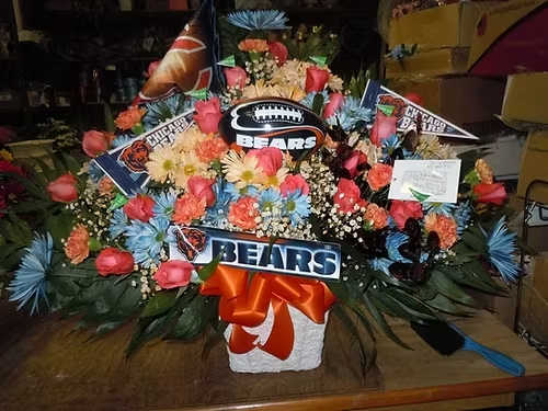 TB29 Sympathy Basket - A mixture of blue tined and orange tinted daisies, orange carnations, orange roses, blue tinted fuji mums, baby's breath, greens and orange bow   Bears items supplied by customer  Banner - $15.00 + extra  Substitutions may apply due to flower availability