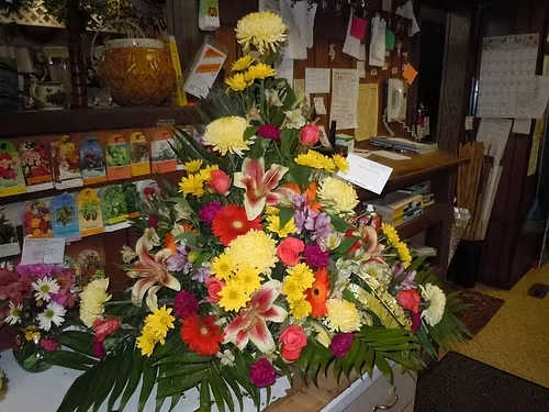TB31 Sympathy Basket - A mixture of yellow daisies, purple carnations, orange roses, yellow fuji mums, red gerbera daisies, shocking lilies, purple alstromaria, baby's breath, greens   Banner - $15.00 + extra  Substitutions may apply due to flower availability