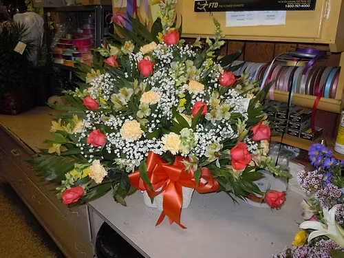 TB33 Sympathy Basket - A mixture of  peach carnations, orange roses, yellow snap dragons, yellow alstromeria, baby's breath, greens and orange bow   Banner - $15.00 + extra   Substitutions may apply due to flower availability