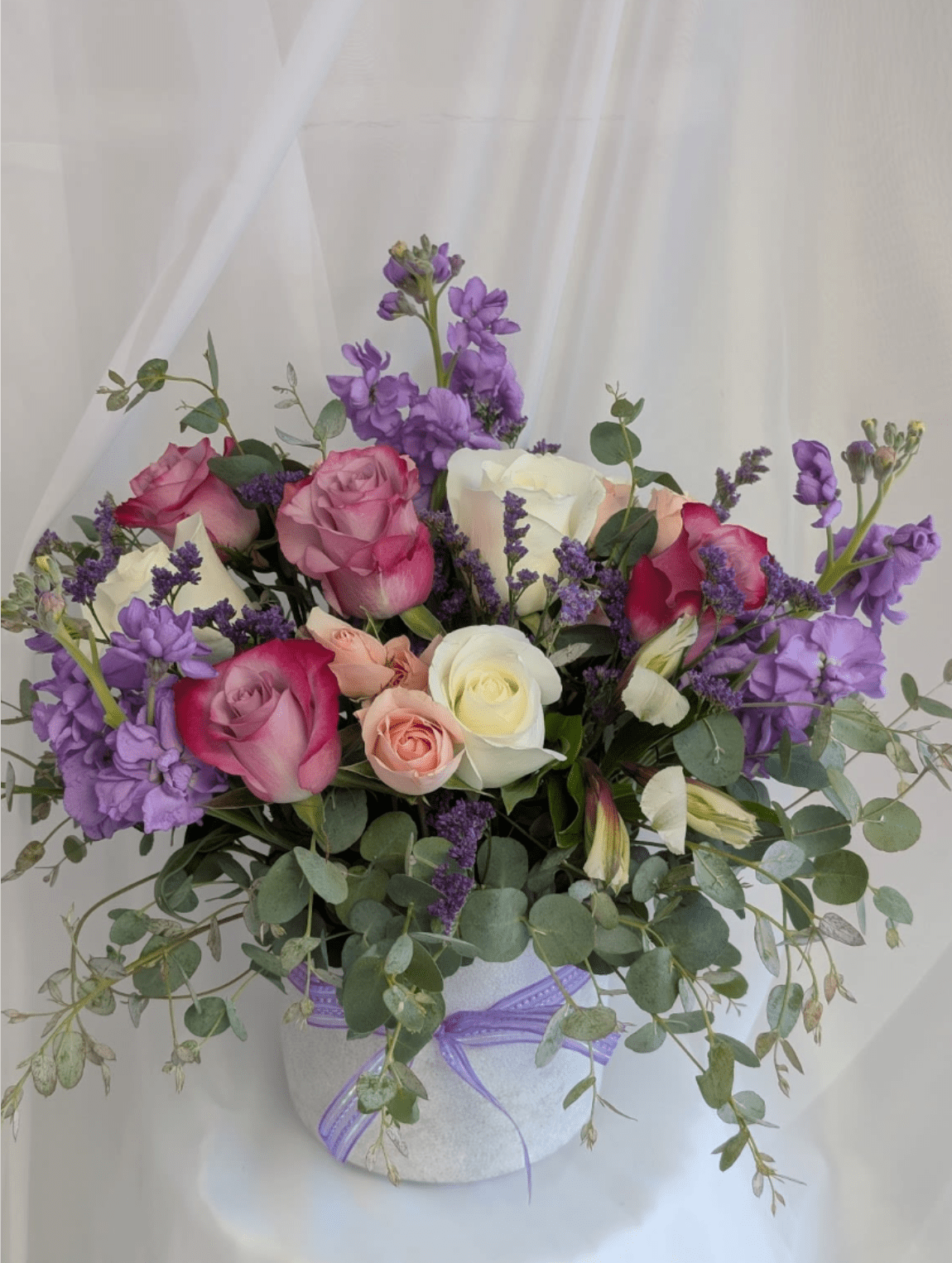 French Kisses - Concrete pot filled with a garden like arrangement of lavender and white roses, Limonium, pink spray roses, eucalyptus, and stocks.