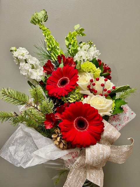 All Wrapped Up - This wrap is ready for the holiday season! Pinecones, winter greens, and an array of white and red flowers make this a beautiful gift. Please note that this design does not come arranged in a vase, the recipient will need to have a vase to place the flowers in. 