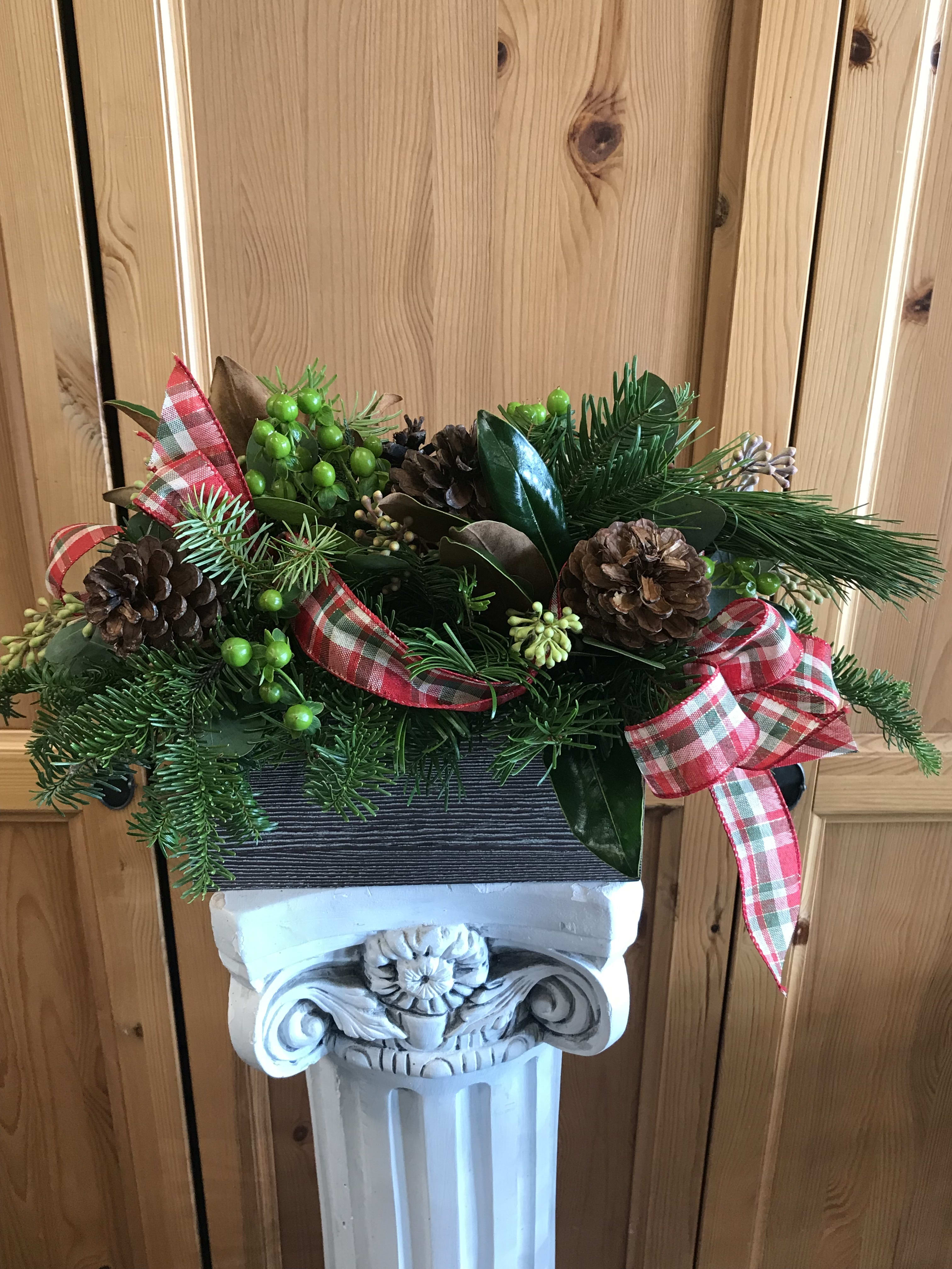 Country Christmas - Long lasting holiday centerpiece in a rectangular faux wood box. Perfect gift for home or office to last the whole holiday season. Our arrangement contains Christmas greens, magnolia, seeded eucalyptus. hypericum, pine cones and country plaid ribbon.