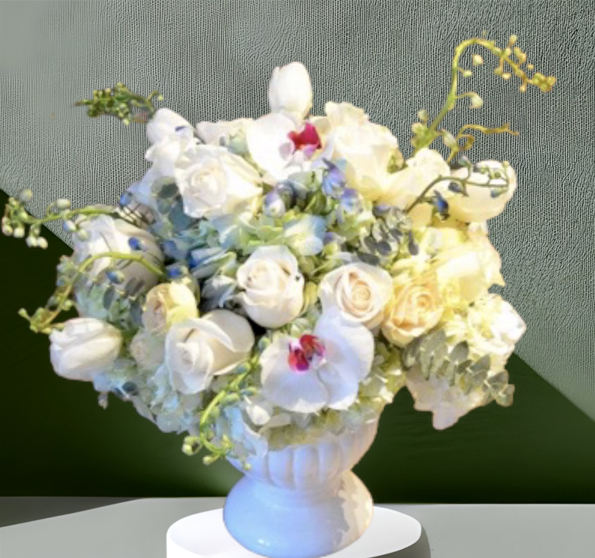 Blue River - A calming mix of baby blue hydrangea, white roses, white tulips, orchids, blue delphinium, and eucalyptus. Arranged in a pedestal vase this beautiful piece is a lovely way to welcome a new baby boy, say "get well soon", or as an expression of sympathy.