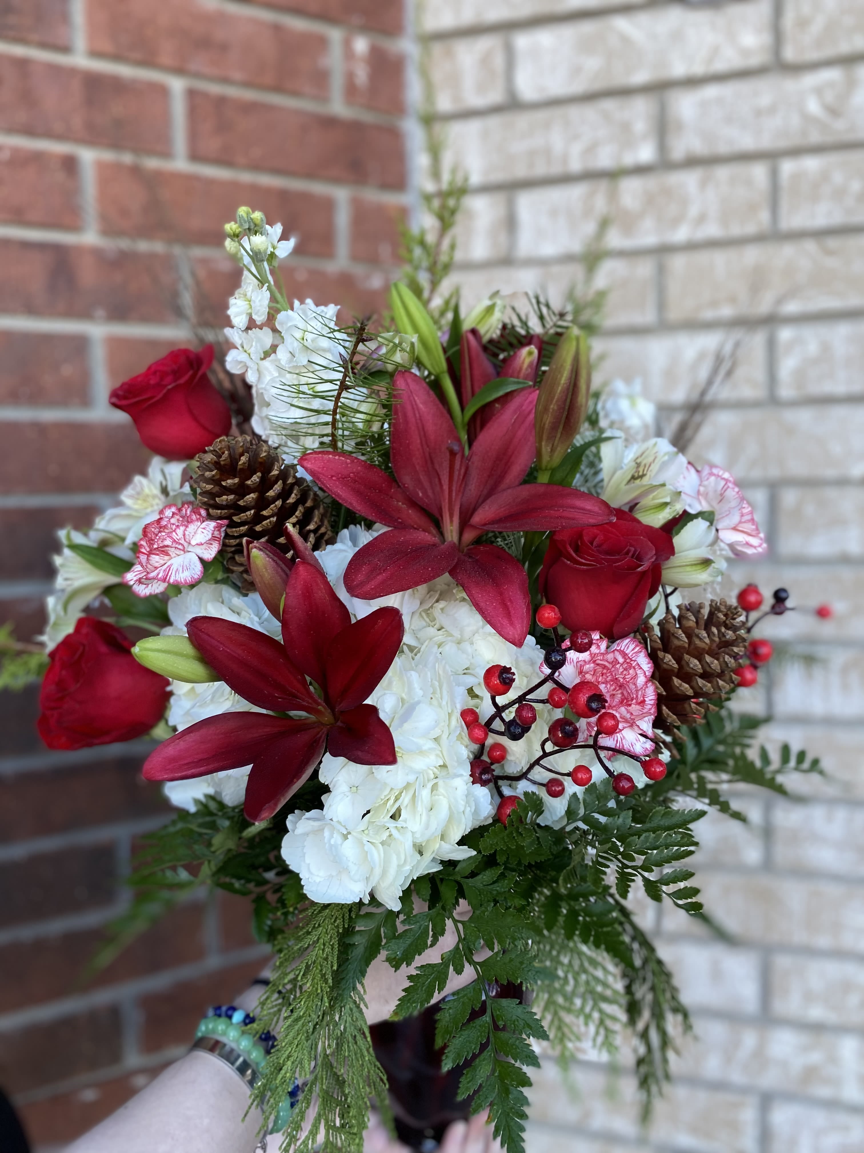 Holiday Harmony Arrangement - Celebrate the magic of the season with our Holiday Harmony Arrangement, a festive blend of rich red blooms, crisp white flowers, and lush winter greens. Vibrant red roses and seasonal favorites pair beautifully with snowy white lilies or mums, creating a cheerful contrast that feels perfectly merry. Fresh evergreens, holly accents, and touches of seasonal textures bring warmth, fragrance, and classic Christmas charm.  Designed to brighten any home, office, or holiday gathering, this arrangement captures the joyful spirit of Christmas in every detail. 