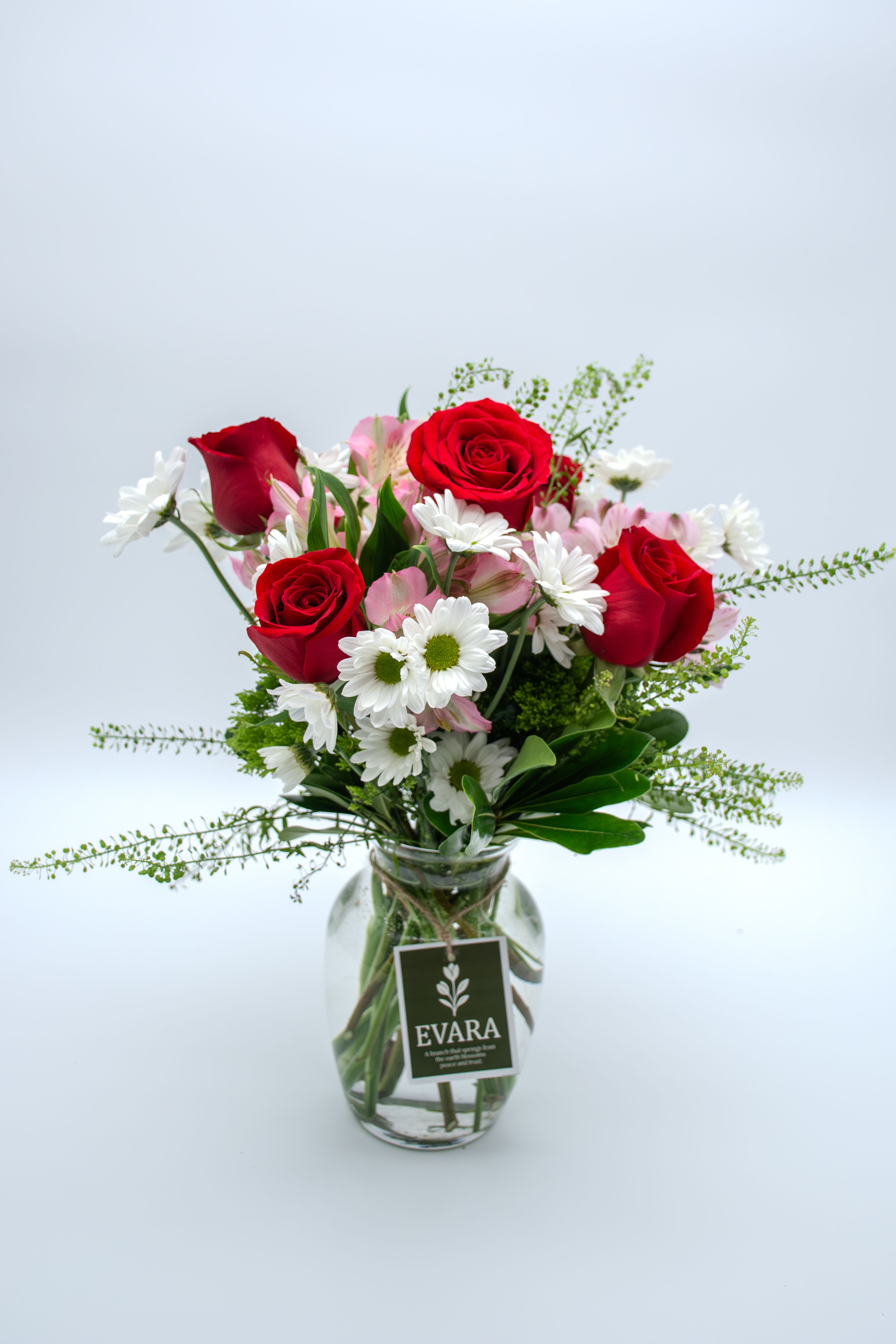 Kisses with Love. - A fresh and charming arrangement that blends the intensity of premium red roses with the softness of white daisies and the delicate touch of pink alstroemerias.