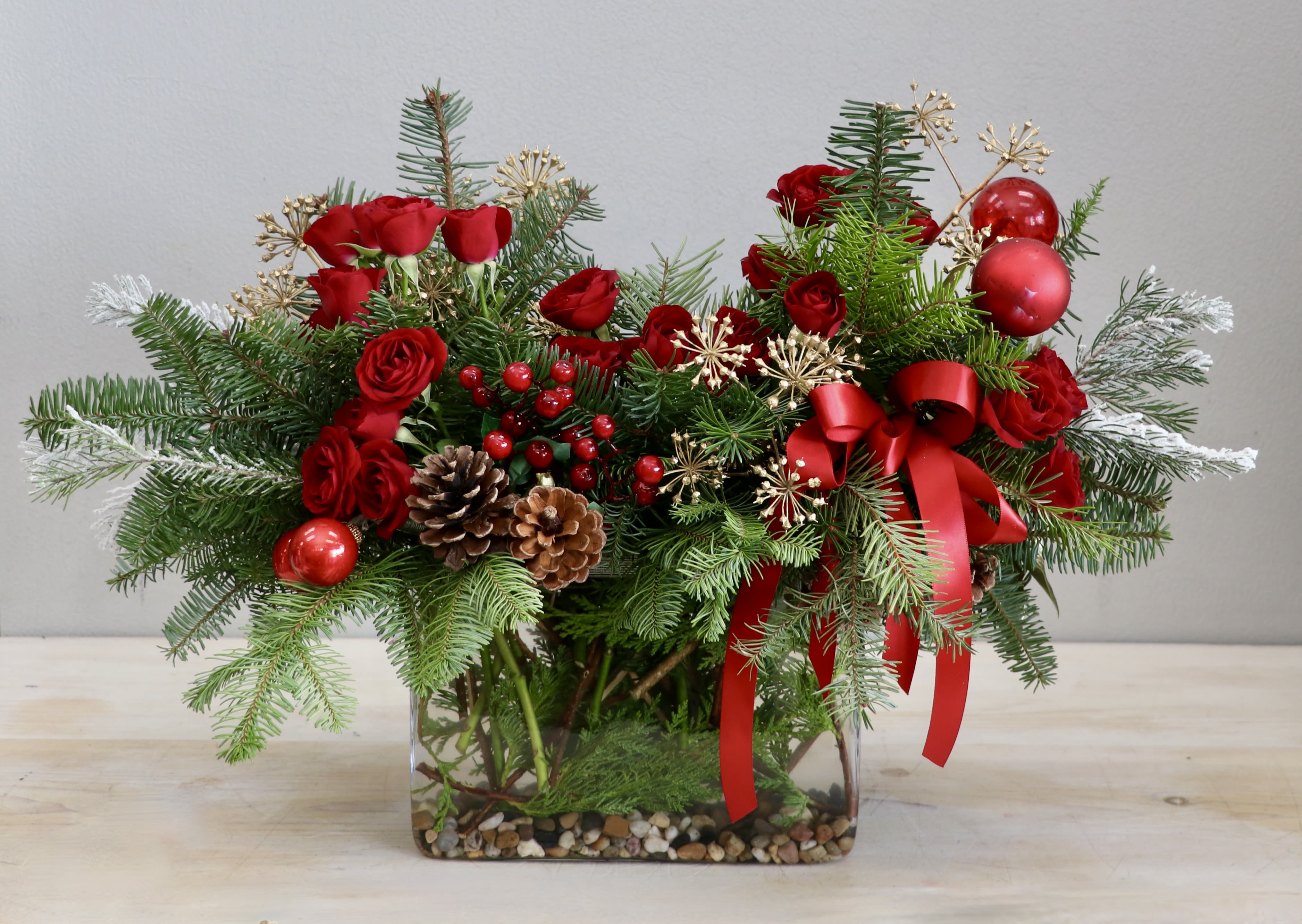 Holly Jolly Reds - Weho  - Just in time for the season, this cheerful arrangement would make the perfect gift for the holidays! We've paired spray roses, with pinecones, and decorative ornaments in a long glass vase. Don't forget to upgrade for more blooms!