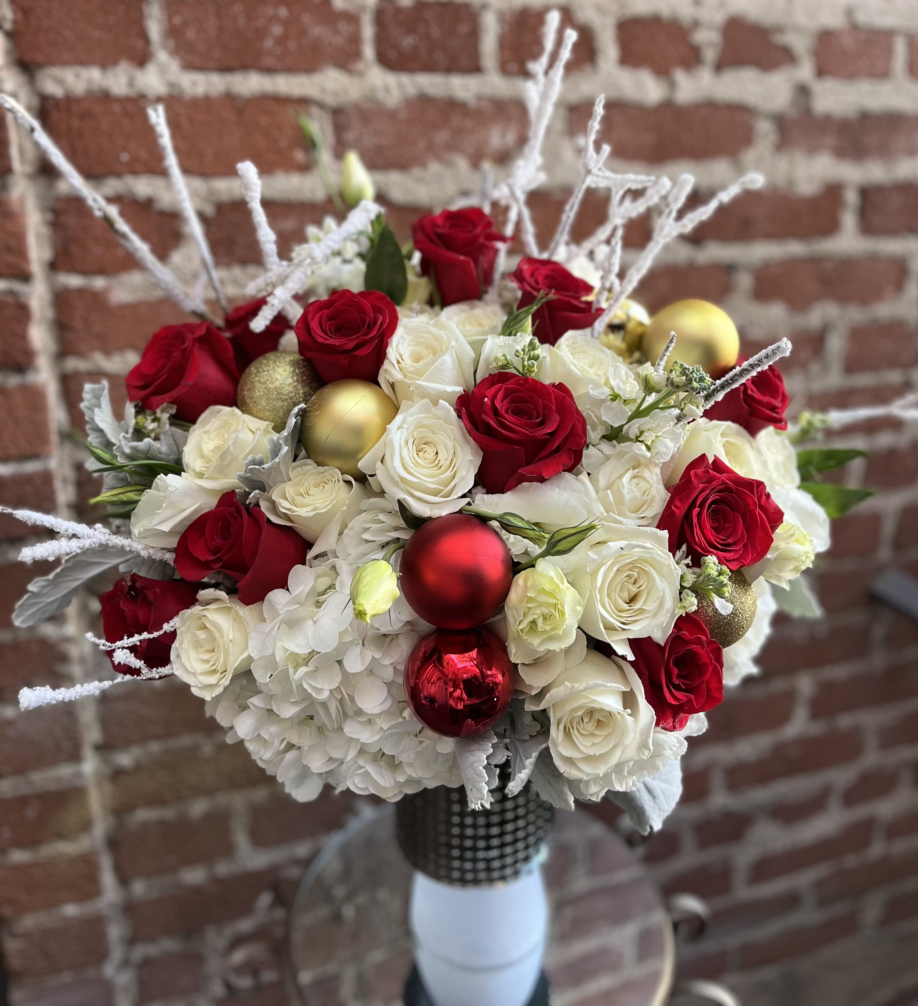 Jolly - Pasadena Flowers  - Introducing "Christmas Joy" – A Festive Floral Symphony Bring the magic of the holiday season into your home with our enchanting Christmas Joy flower arrangement. This exquisite creation is more than just a centerpiece; it's a celebration of the joy and warmth that Christmas brings. Handcrafted with care and attention to detail, Christmas Joy is a captivating arrangement that combines the traditional charm of Christmas with the timeless beauty of fresh flowers. Lush evergreen foliage forms the perfect backdrop for an array of festive blooms, including vibrant red roses, snowy white lilies, and delicate sprigs of holly.  