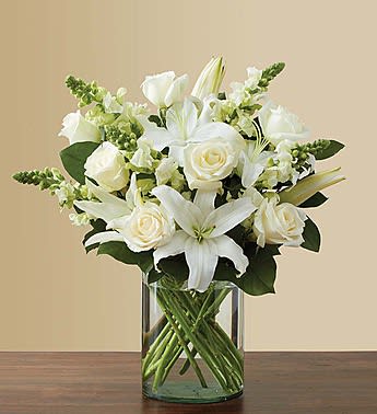 Pure Love (Classic All White) - Crisp white flowers have a certain timelessness and elegance... and this luxurious arrangement is no exception! Striking white roses, lilies and snapdragons are hand-gathered by our skilled florists with touches of lush greenery inside a stylish cylinder vase. No matter what it is you’re trying to say, we can’t think of a more beautiful gift to say it with.