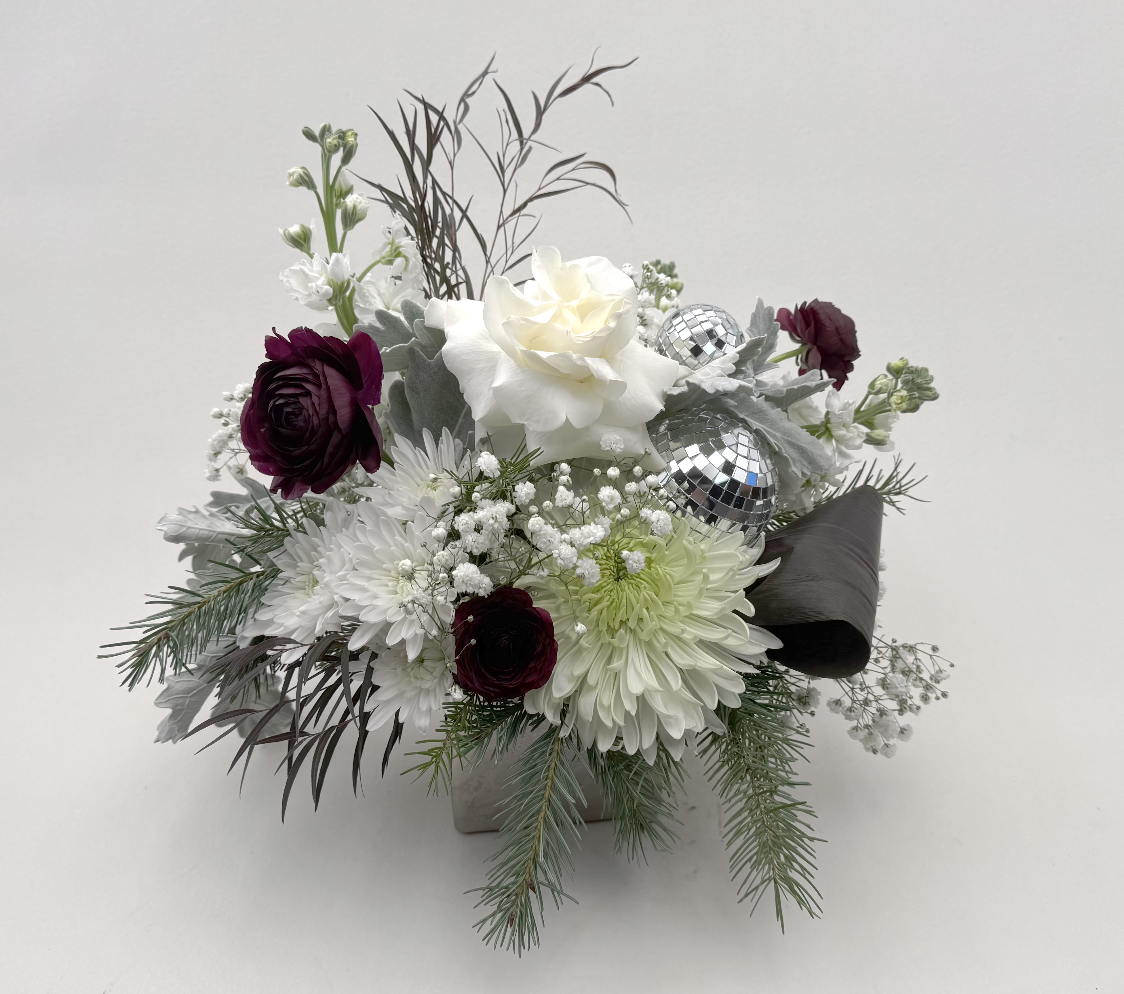 Happy New Year!  - Ring in the new year with our Happy New Year festive flower arrangement! White and dark burgundy flowers wiith wintergreens are arranged in a 4"x4" silver glass vase.   Delivery Info- We make all of our deliveries after 1pm every day. If the weather is very cold, we prefer not to leave the flowers outside. Please let the recipient know that they should expect delivery. 