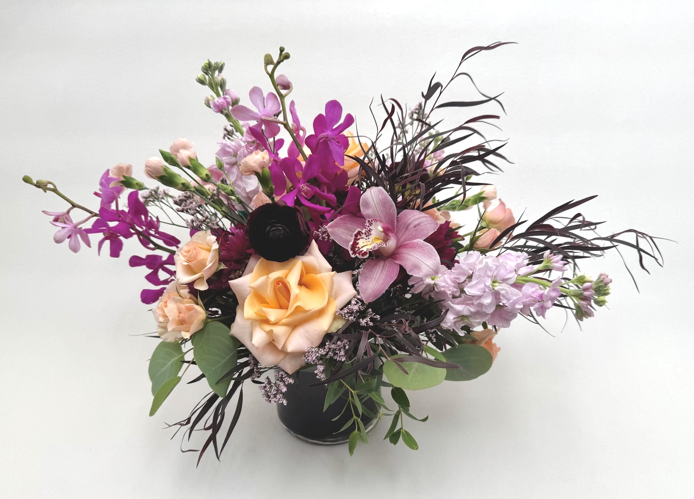 Jolene - Your beauty is beyond compare...Jolene is bold and beautiful with soft peach, purple, burgundy, and pink flowers that are arranged in a glass vase with a ti leaf wrap.    Delivery Info- We make all of our deliveries after 1pm every day. If the weather is very cold, we prefer not to leave the flowers outside. Please let the recipient know that they should expect delivery. 