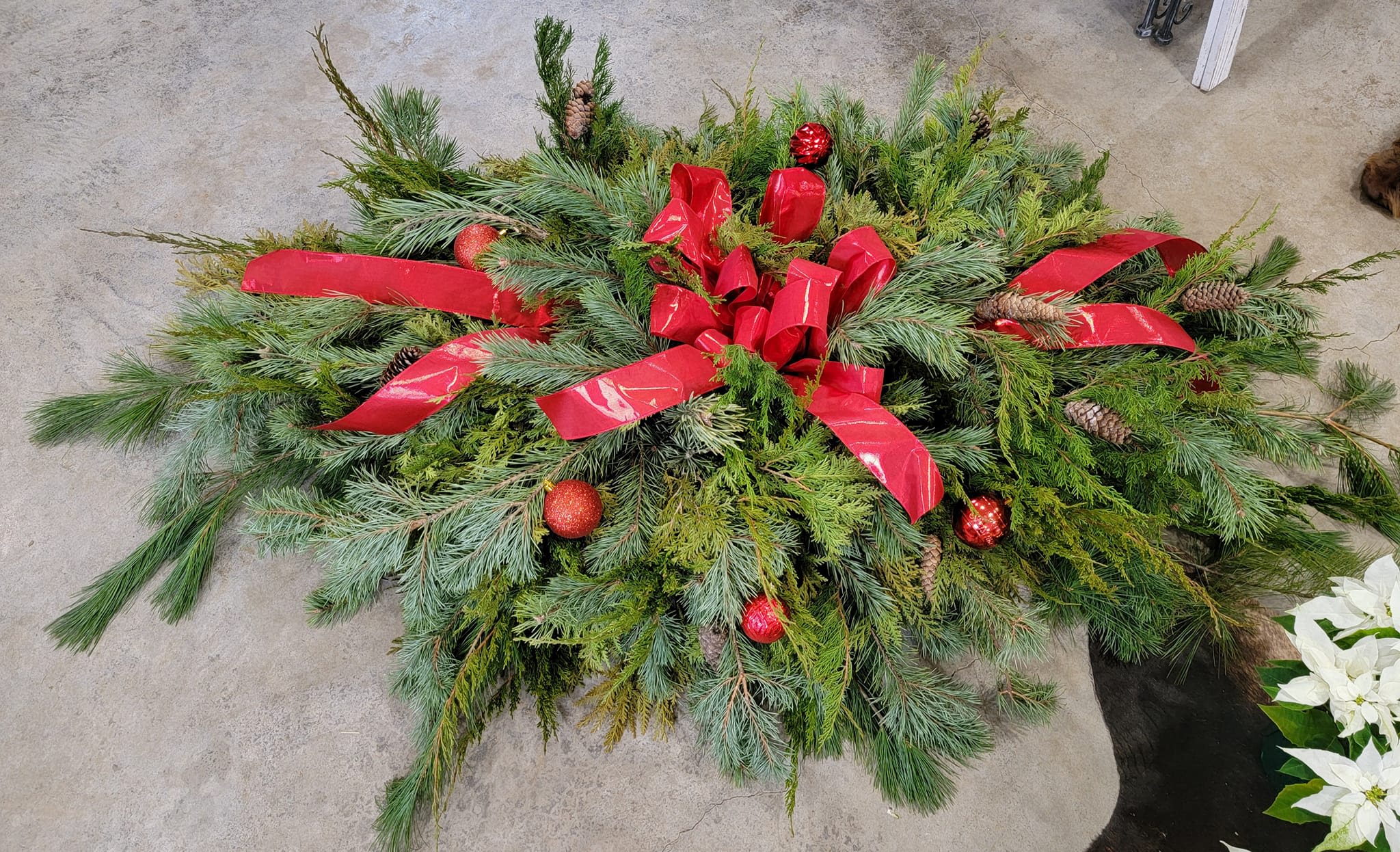 Cementary Grave Blanket  - Honor your loved ones this holiday season with a full size fresh pine grave blanket. Full of texture with three different types of pine dressed up with your choice of color bow, Christmas bulbs, and pine cones. Ground stakes are not included. 