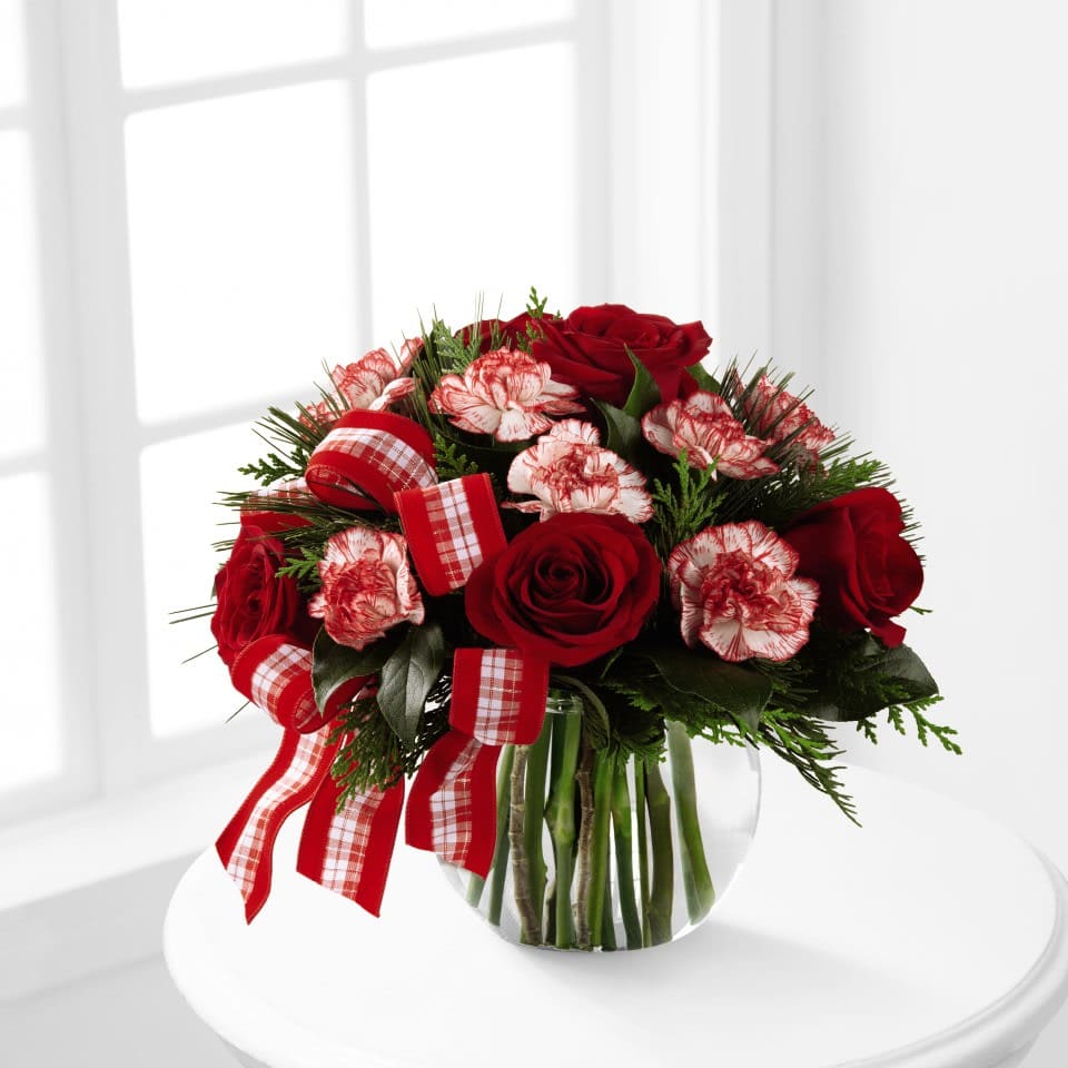 FTD® Winter Elegance™ Bouquet - The FTD® Winter Elegance™ Bouquet offers warm wishes and bright sentiments for a wonderful holiday season! Rich red roses and peppermint carnations are delicately arranged amongst holiday greens to create a festive display. Arriving in a clear glass bubble bowl and accented with a red and white plaid ribbon, this arrangement is full of seasonal sophistication.  