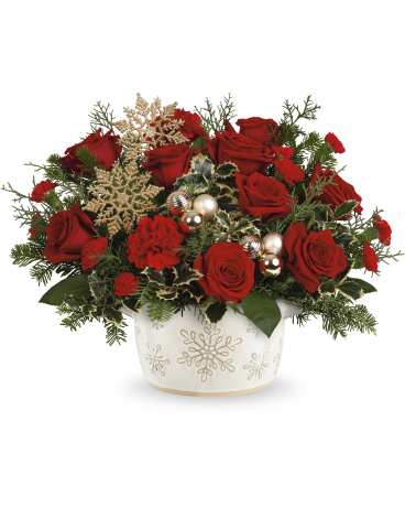 Snowflake Symphony Bouquet - Celebrate the spirit of Christmas with this enchanting red rose bouquet, artfully arranged in a timeless stoneware serving dish centerpiece. Hand-painted and food-safe, it's adorned with charming snowflake details, adding a delightful touch of seasonal cheer. Snowflake Symphony Centerpiece features vibrant red roses, classic red carnations, and miniature red carnations, along with variegated holly, noble fir, and cedar. 