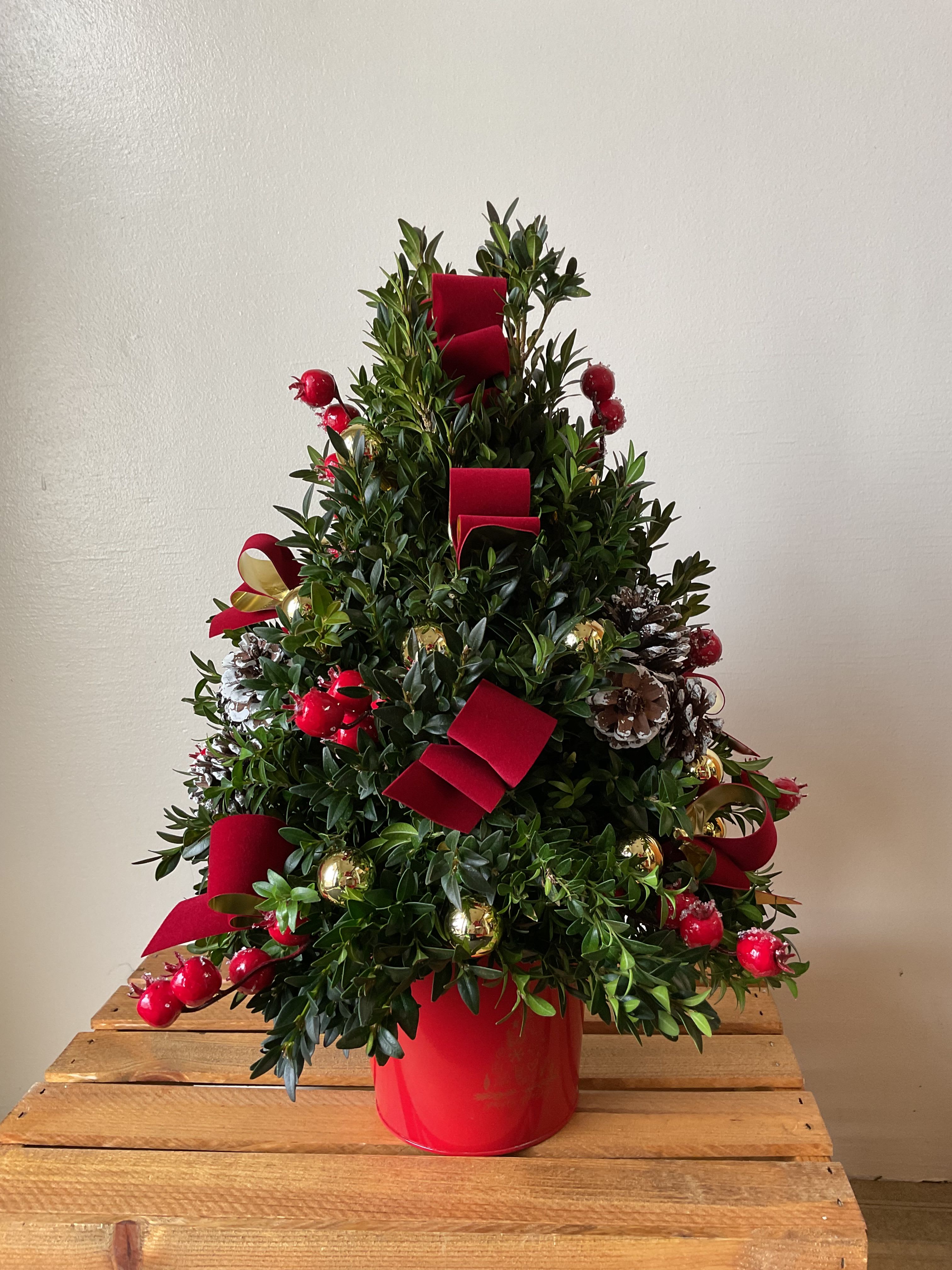 Boxwood Tree - Each tree is one of a kind. Fresh boxwood arranged into the shape of a tree decorated with an abundant amount of holiday decorations. Start a new tradition this year by sending your loved one this very special tree.