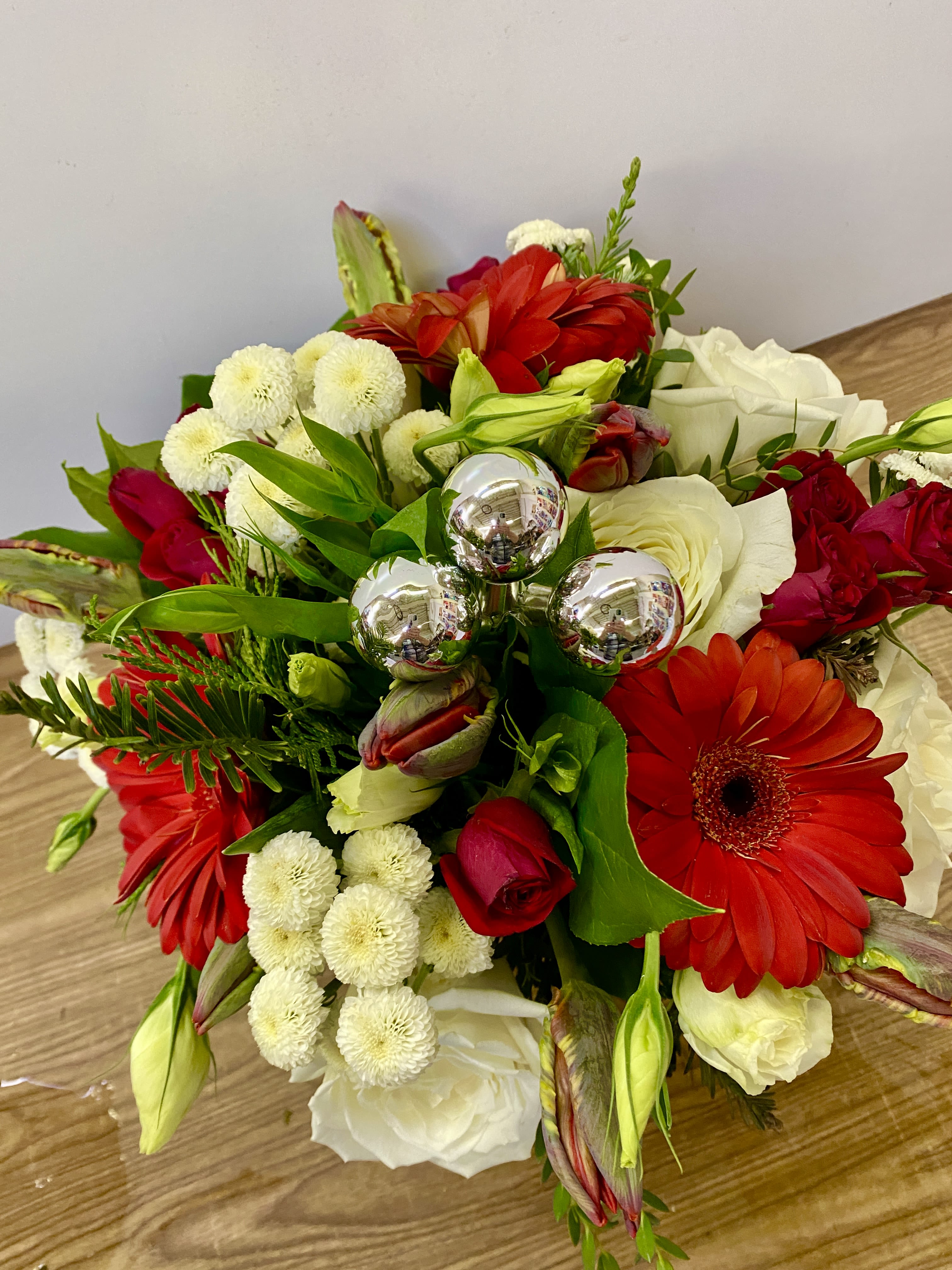 SANTA BOOTCAMP - In a glass of waves Christmas greenery with a red Gerber, red tulips, red roses, and white moms