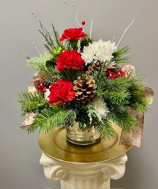 SANTA'S HELPER - This long lasting design is a lovely gift for anyone on your list! Mixed winter greens, carnations, and daisy cushion mums will last long after the holiday season. This is designed in a glass vase that is lined with a white birch liner.