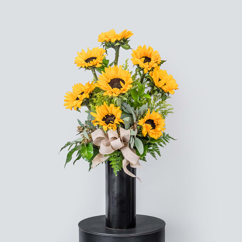Sunshine Shimmer - This beautiful arrangement is an sweet touch for any occasion with beautiful sunflowers, bright solidaster and beautiful greens that will give it a bit of sunshine for any occasion.  32"H X 20"W
