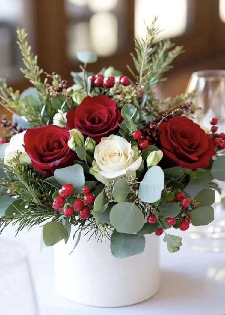 Christmas Rose Blessing - A charming and heartfelt holiday arrangement, "Christmas Rose Blessing" brings together the timeless beauty of deep red roses, and a soft glow of an white roses, symbolizing love, peace, and togetherness during the Christmas season. Bright red winter berries, eucalyptus, and fragrant evergreen sprigs add festive texture and natural holiday fragrance, making the bouquet feel both cozy and sophisticated.  Arranged in a vase, this design offers a fresh, modern Christmas look- perfect for gifting, decorating a holiday table, or bringing a touch of warmth to any winter celebration.