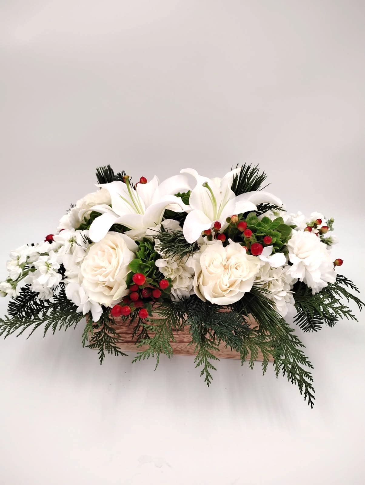 Cheerful Centerpiece - Celebrate the season with a timeless and fragrant holiday arrangement designed to bring warmth and sophistication to any table. This Christmas centerpiece features lush, aromatic cedar layered with seasonal greenery to create a natural, woodland-inspired foundation. Nestled among the foliage are clusters of vibrant red hypericum berries, adding festive color and a touch of winter charm.