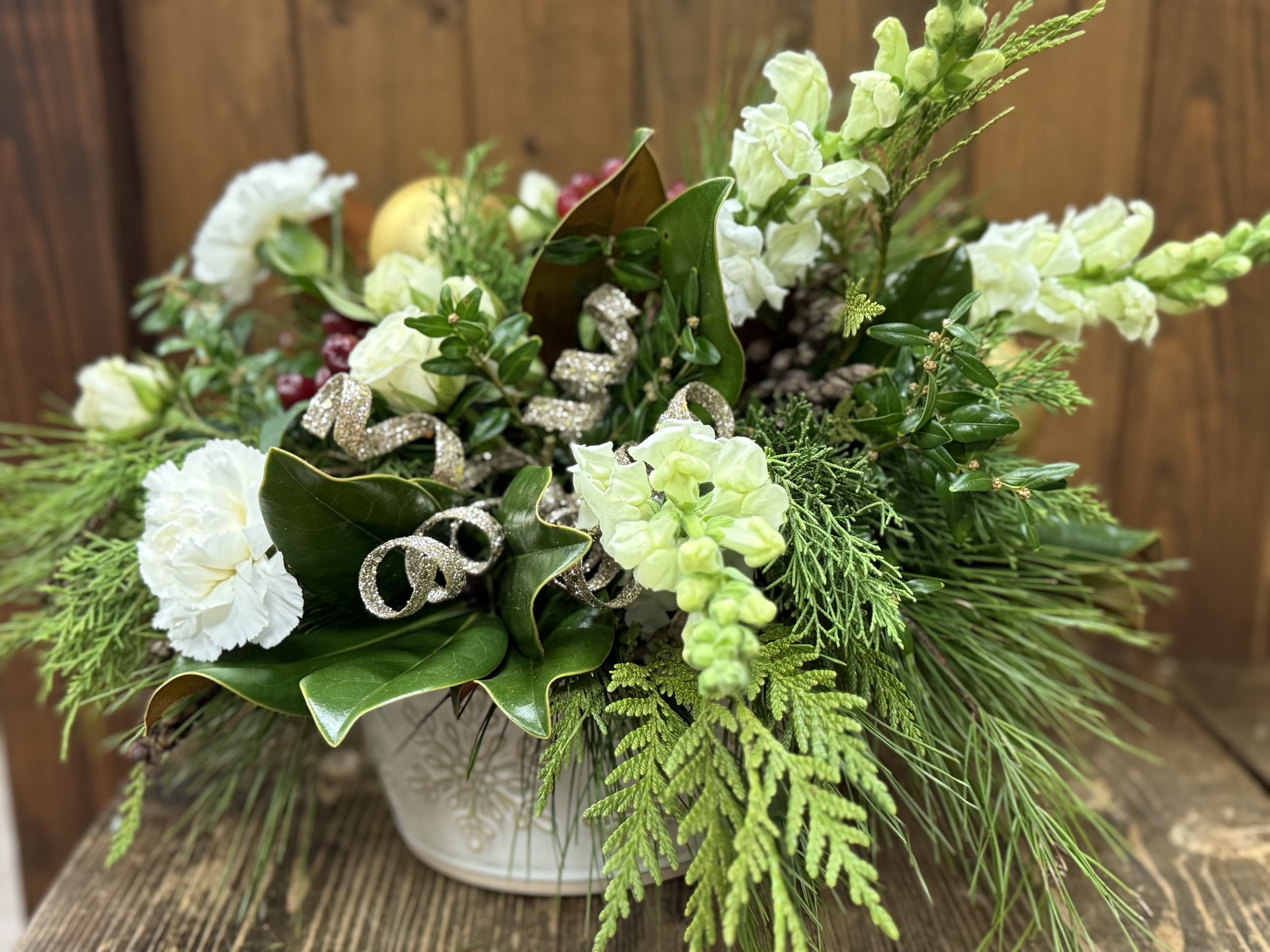 Winter Wonderland - This enchanting holiday arrangement is a true celebration of the season, nestled in a charming snowflake stoneware baking dish. The dish is filled fragrant Christmas greens and accentuated with ornaments, pine cones and dried fruit. 