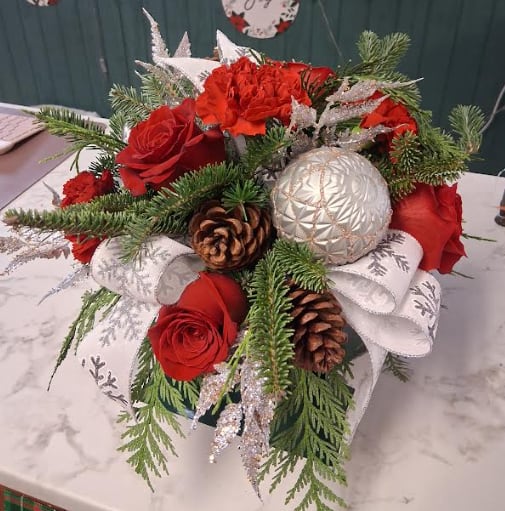 Snowflake - Elegant, crisp, and full of winter wonder, Snowflake captures the beauty of a frosty December morning. Designed with snowy white blooms, soft seasonal greens, and shimmering icy accents, this arrangement sparkles with quiet sophistication. Touches of silver, frosted textures, and delicate winter details make it a perfect gift or a stunning addition to your holiday décor—bringing the magic of a single snowflake to life.