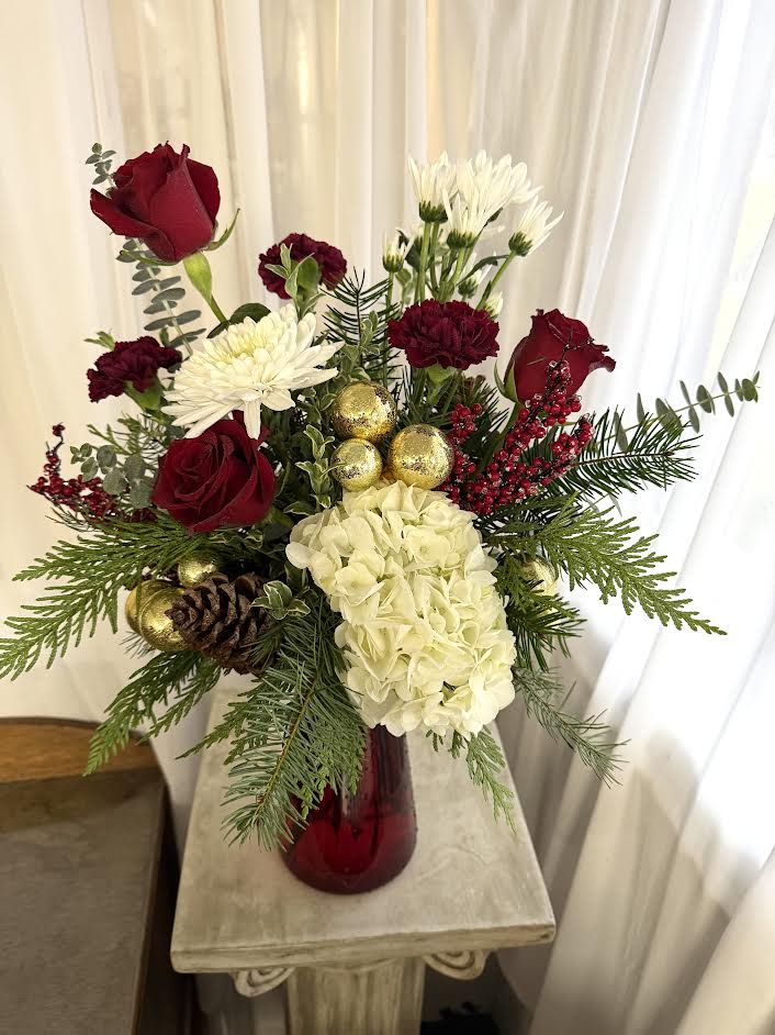 I'll Be Home for Christmas - A tall vase of Christmas greens, roses, and more!  Call the shop to find out exactly what we'll be using because inventory constantly changes.