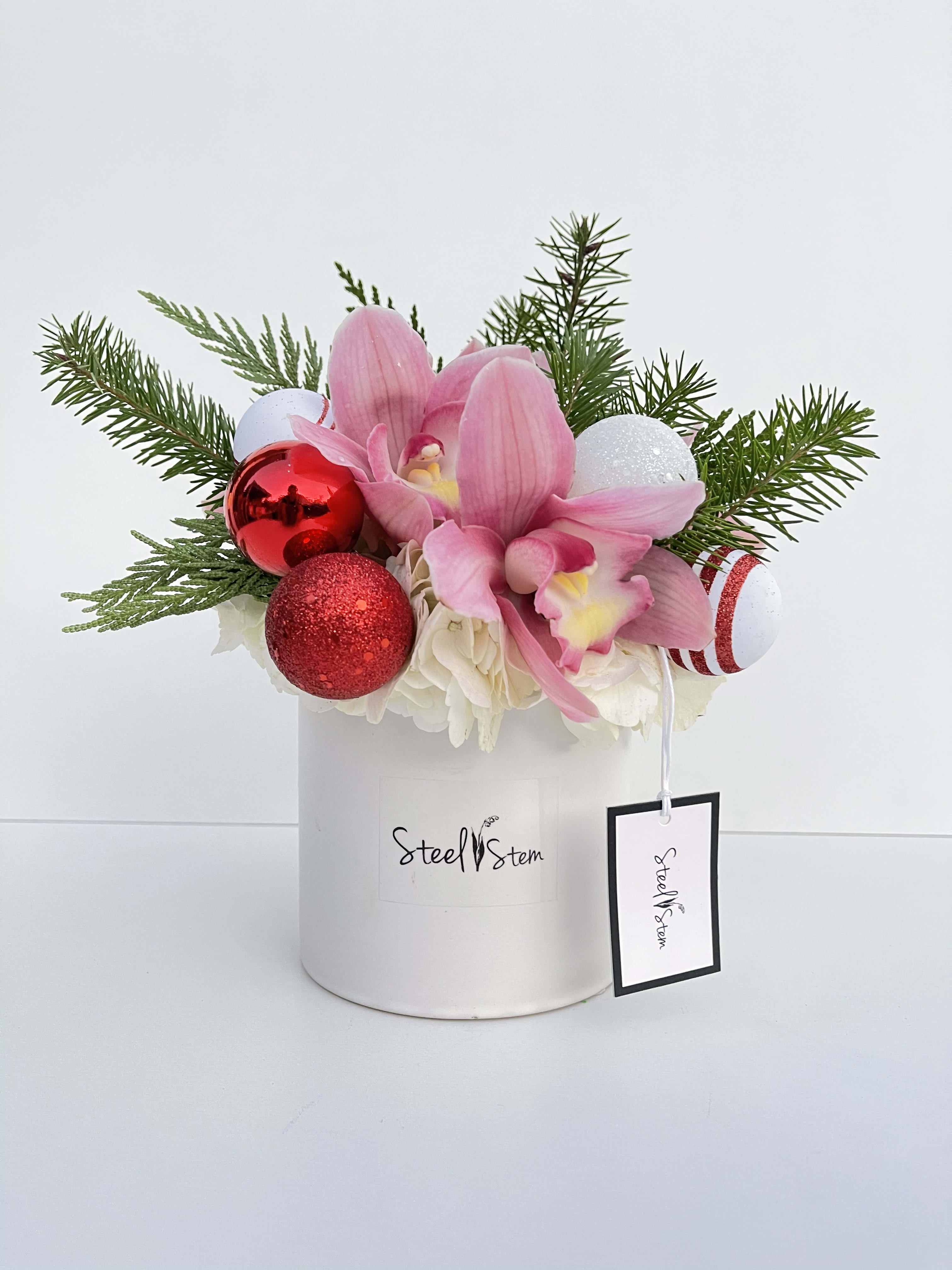 Candy  - Our Candy Cane arrangement has a high quality glossy ceramic vase, pink cymbidium orchids, white hydrangea, touch of pine greens, white ornaments and red ornaments. Perfect gift too enjoyed in this Special holidays.