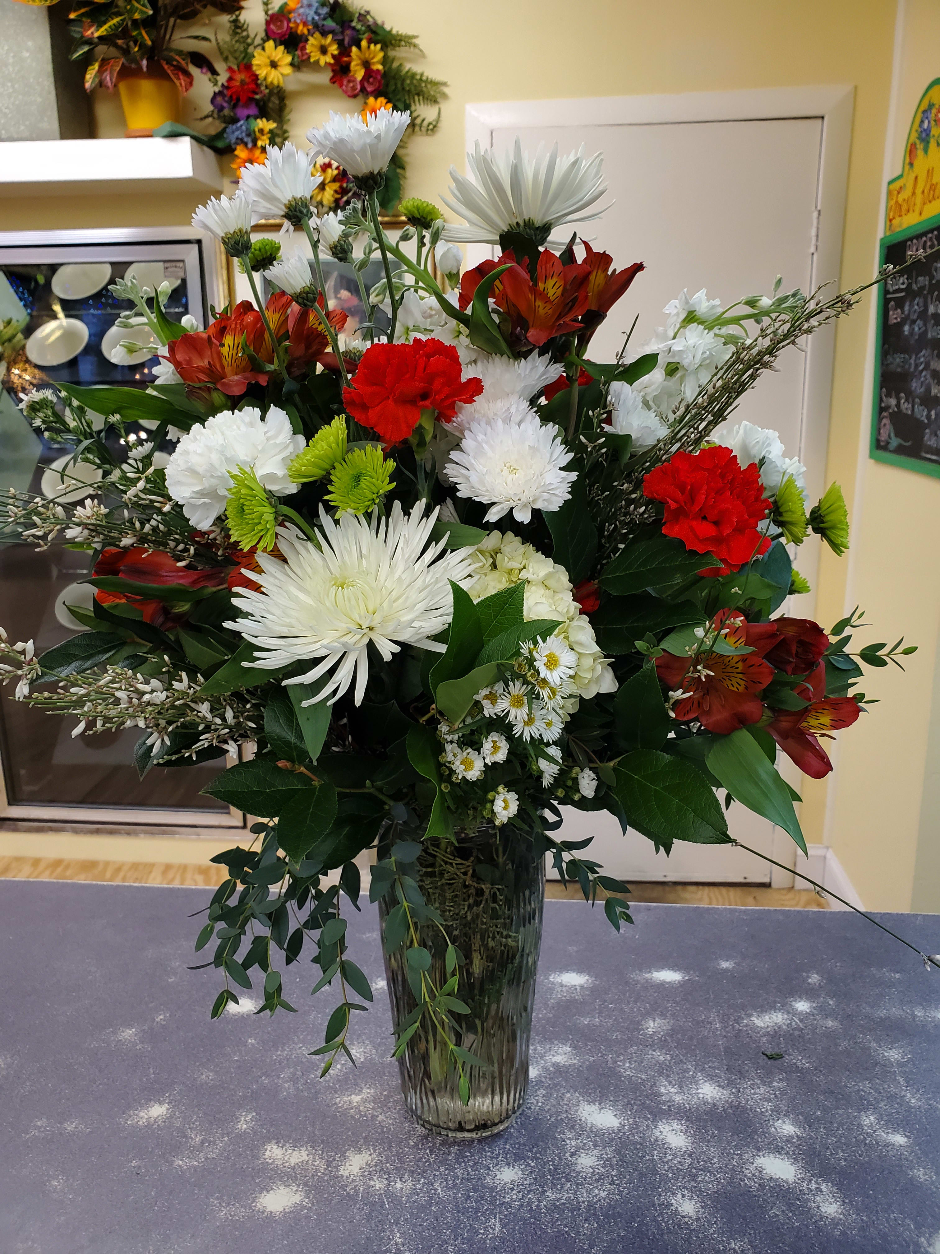 Grand Christmas  - Large presentation of seasonal flowers and winter greens. Arranged in a glass vase.