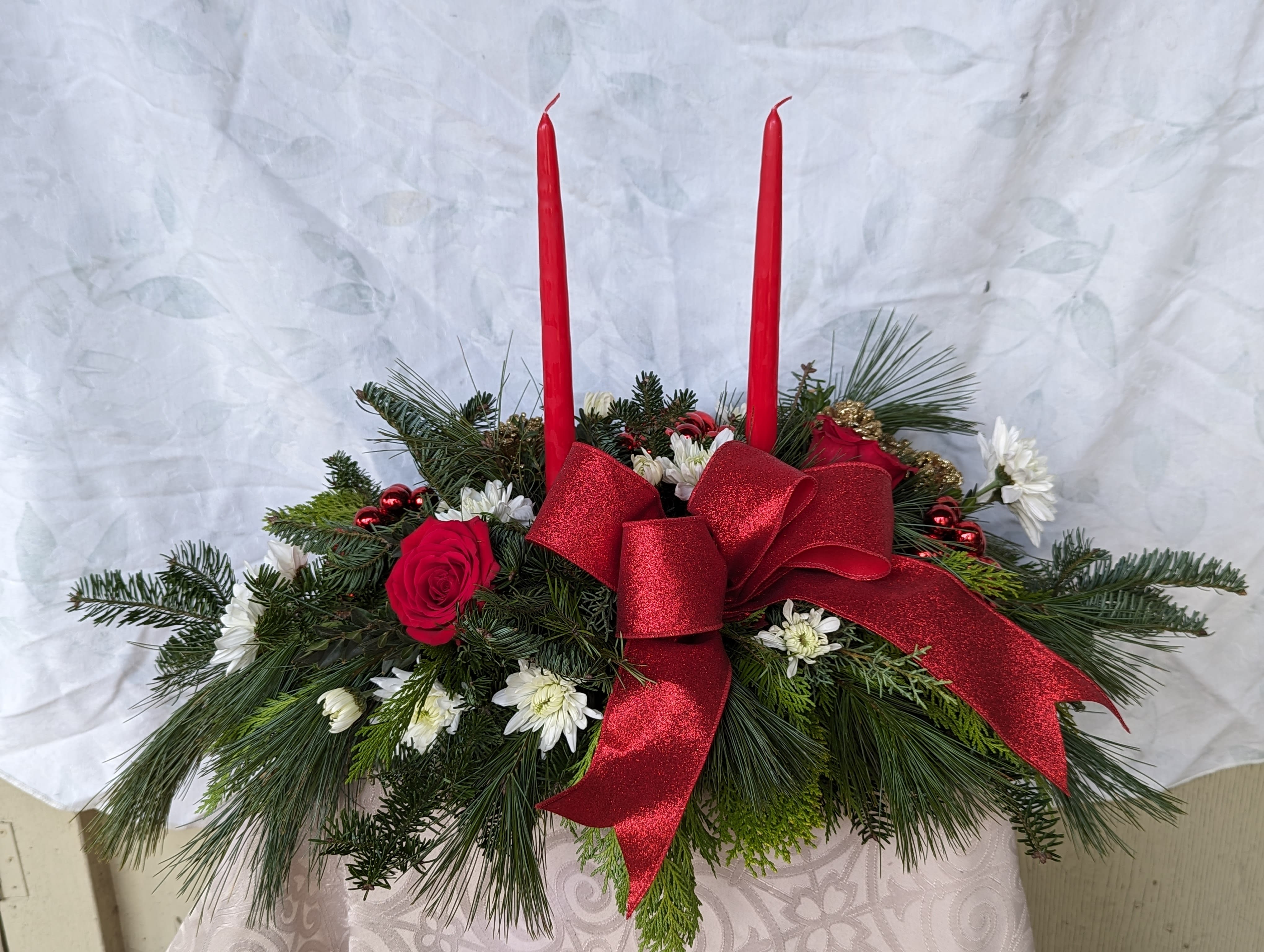 All Wrapped Up - Red and white centerpiece with two tapered candles adorned with a red bow. 
